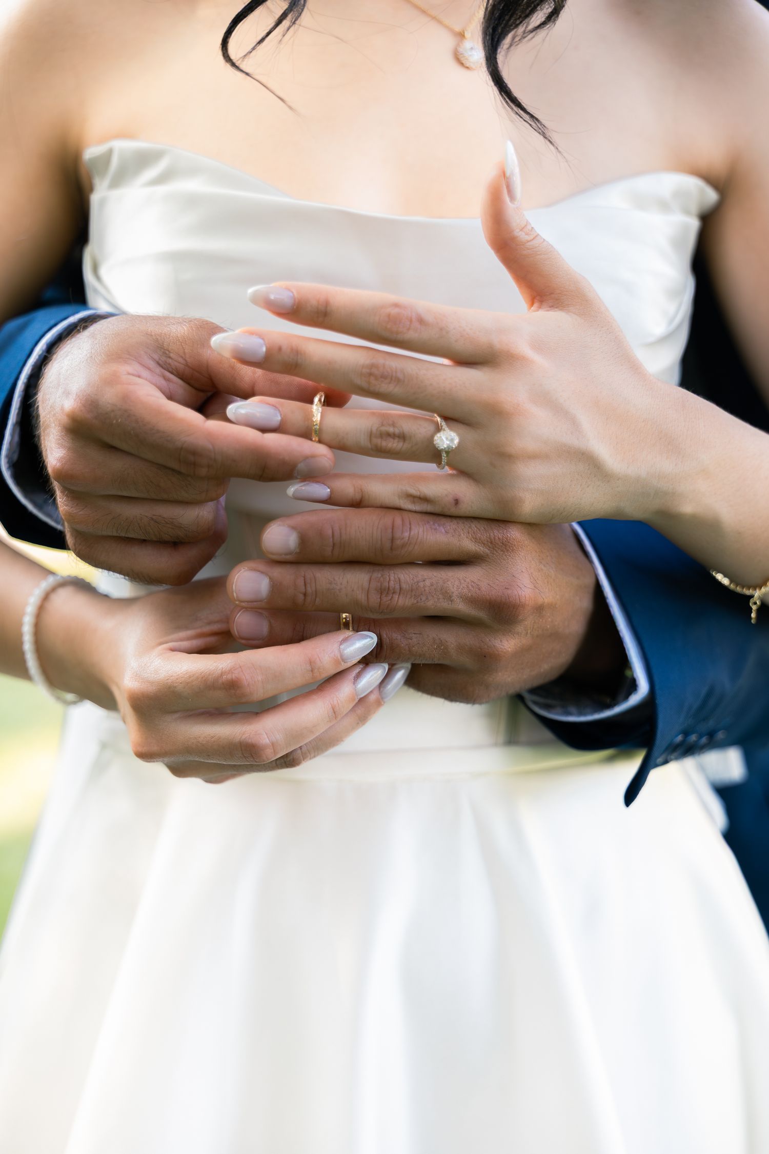 Close-up sequence showing wedding rings being exchanged between hands against a white dress background.