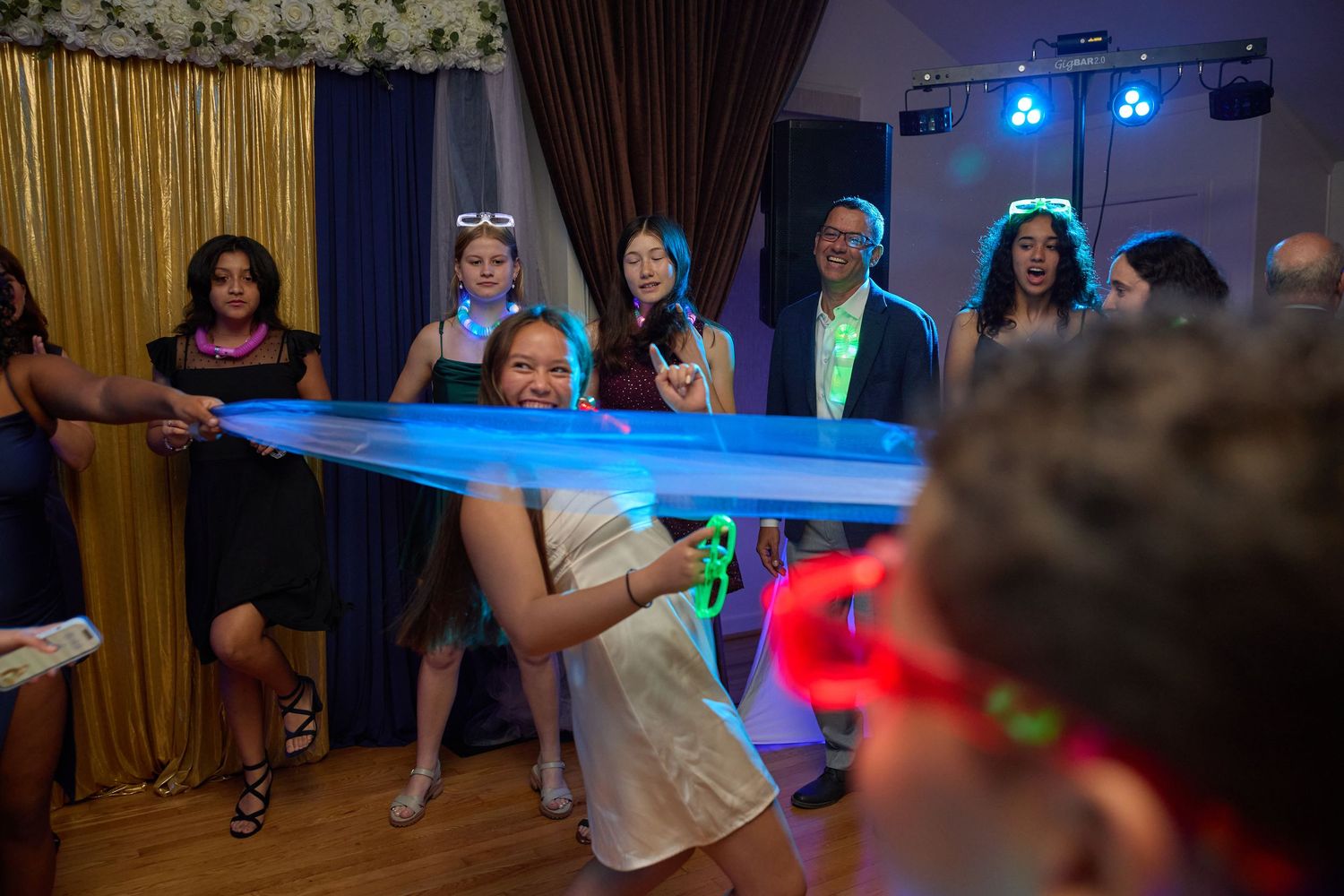 Wedding reception dance floor filled with guests enjoying themselves under colorful party lighting.