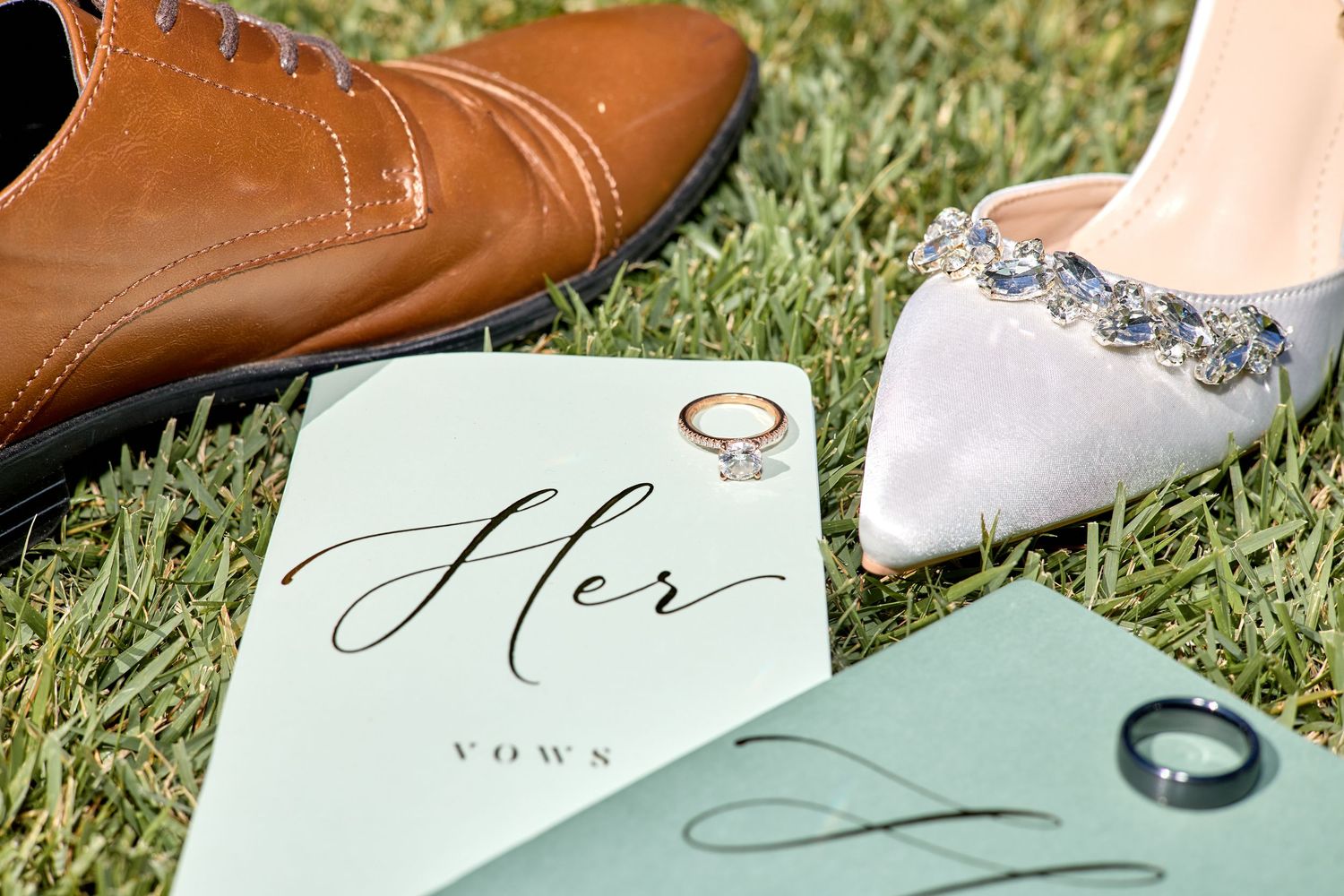 Wedding shoes and mint green cards arranged artistically on grass with elegant calligraphy.