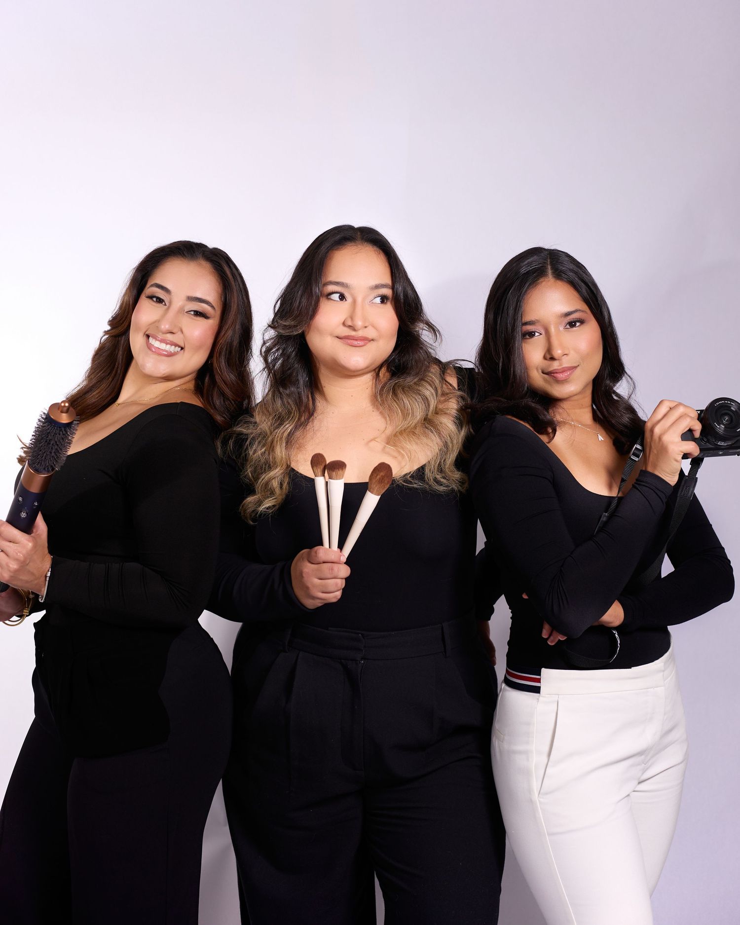 A group poses together wearing coordinated black and white outfits against a light studio background.