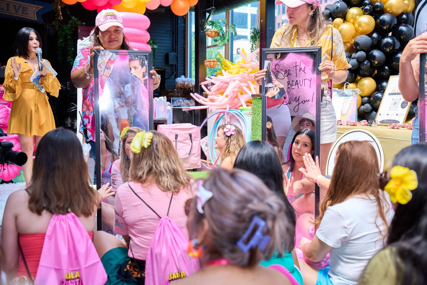 Colorful birthday party celebration with guests in pink outfits surrounded by balloons and festive decorations.