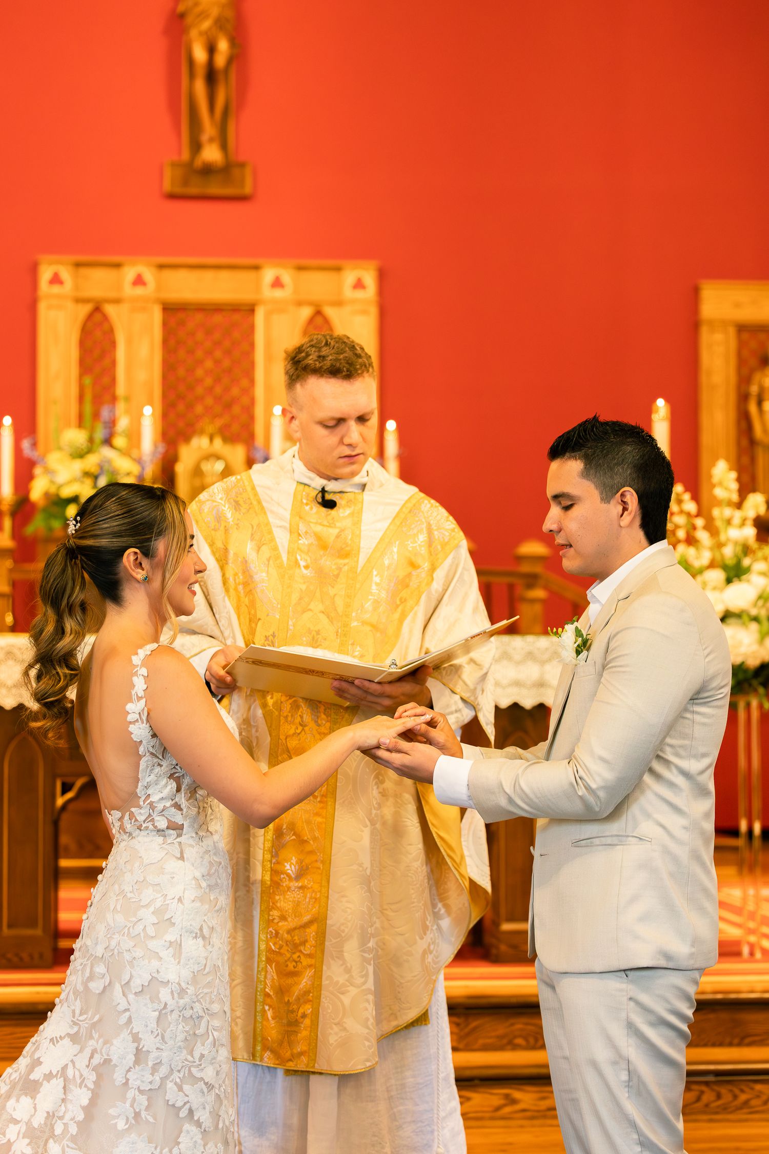 A couple dances together in a church with red walls and golden decor during a wedding celebration.