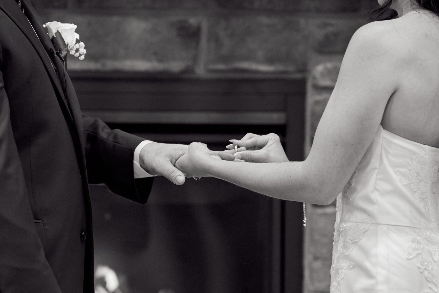 A couple exchanges rings during a wedding ceremony in black and white.