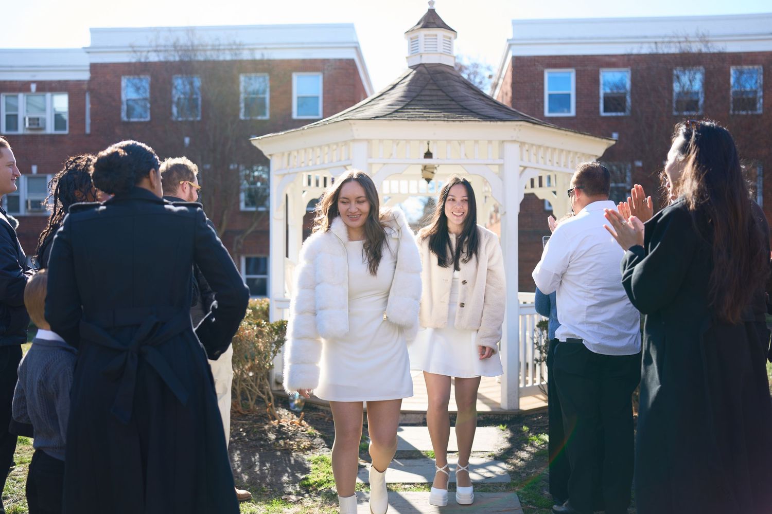 Students gather outside a brick building during a college campus event with people mingling in casual attire.