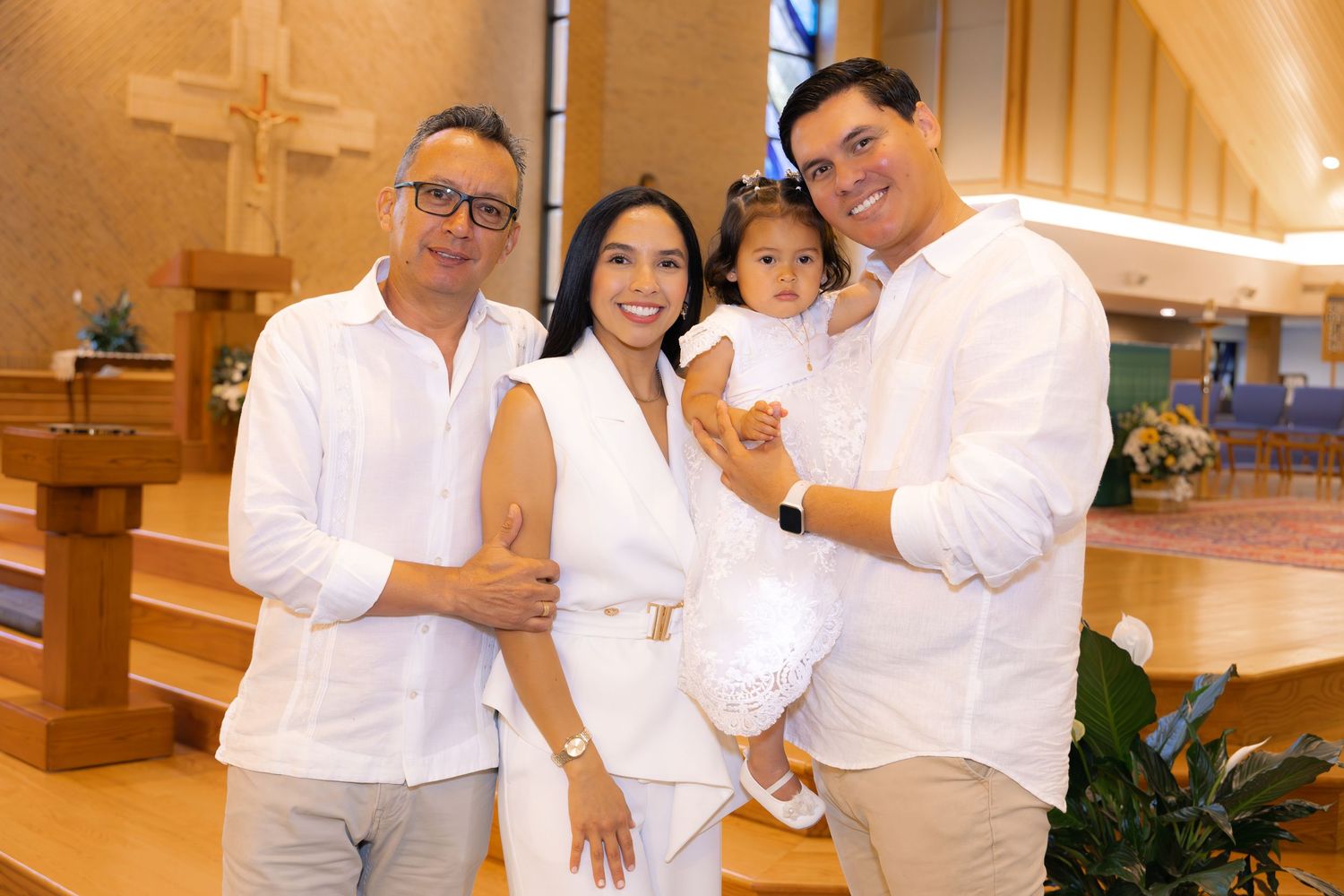 Group photo in a church with everyone dressed in white and neutral tones.