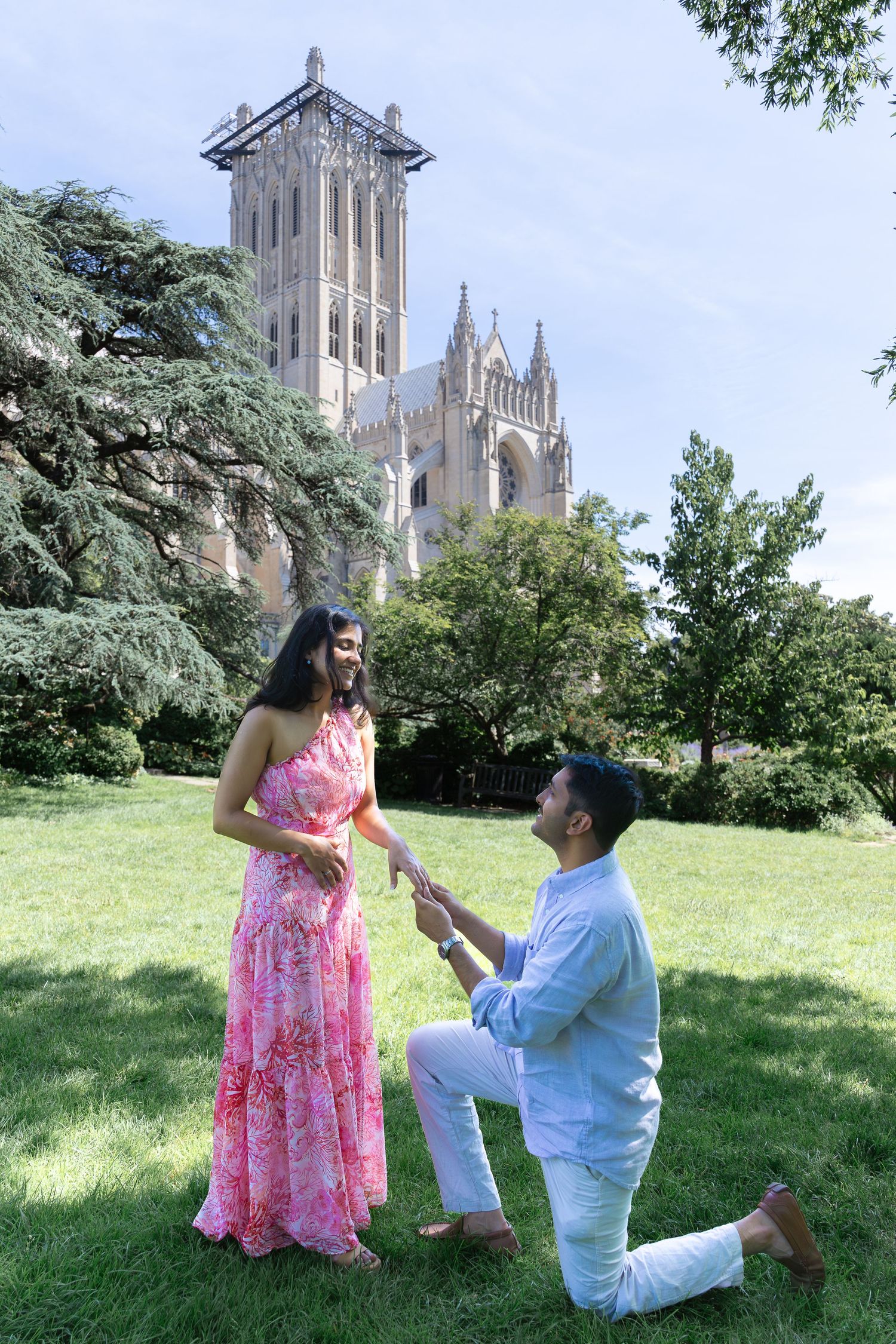 A couple shares a romantic marriage proposal moment on the lawn in front of the National Cathedral in Washington DC.