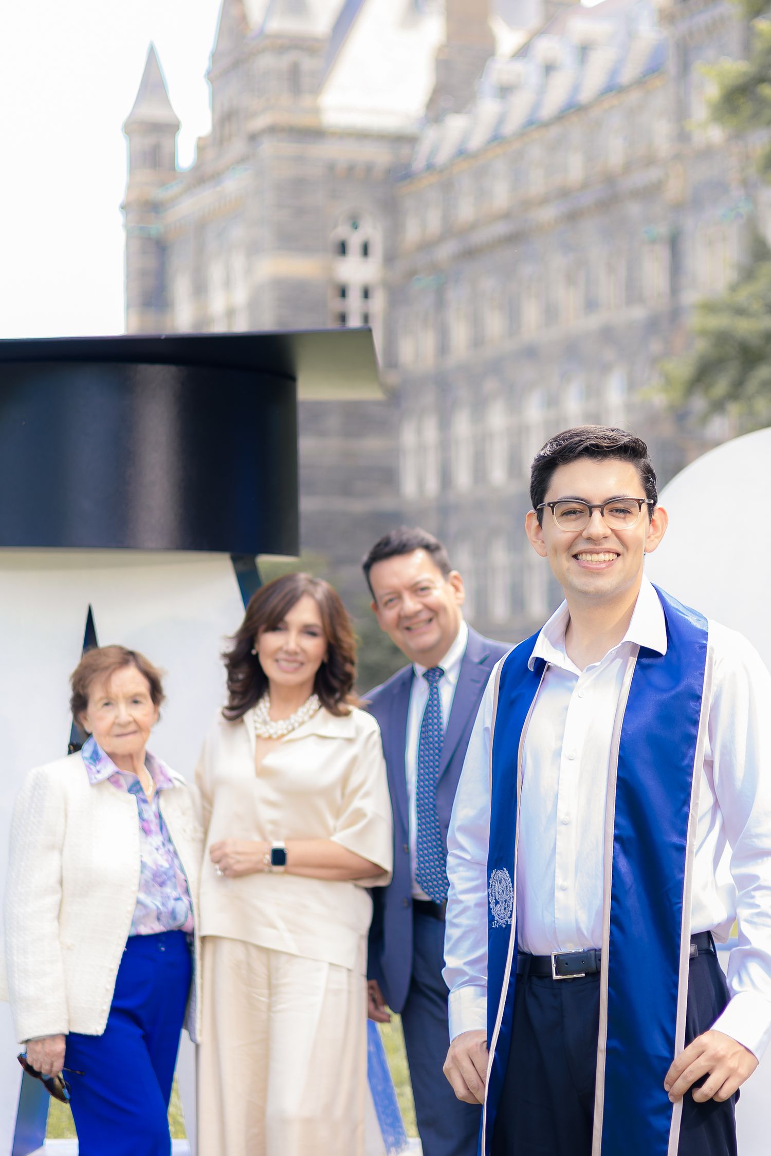 A group of people wearing formal attire pose together outside a grand architectural building.