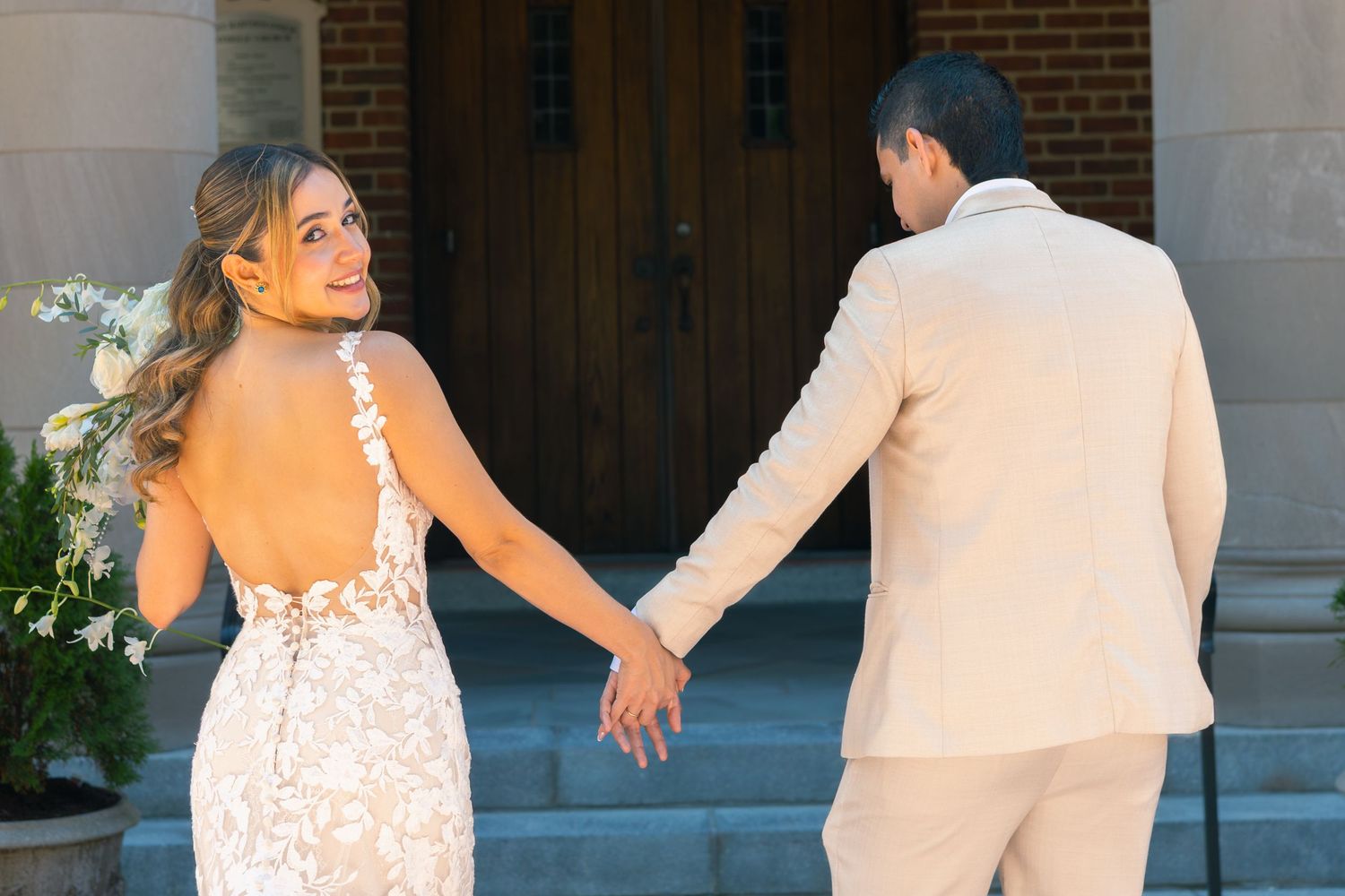 A couple in wedding attire dances together during their first dance at an elegant brick venue.