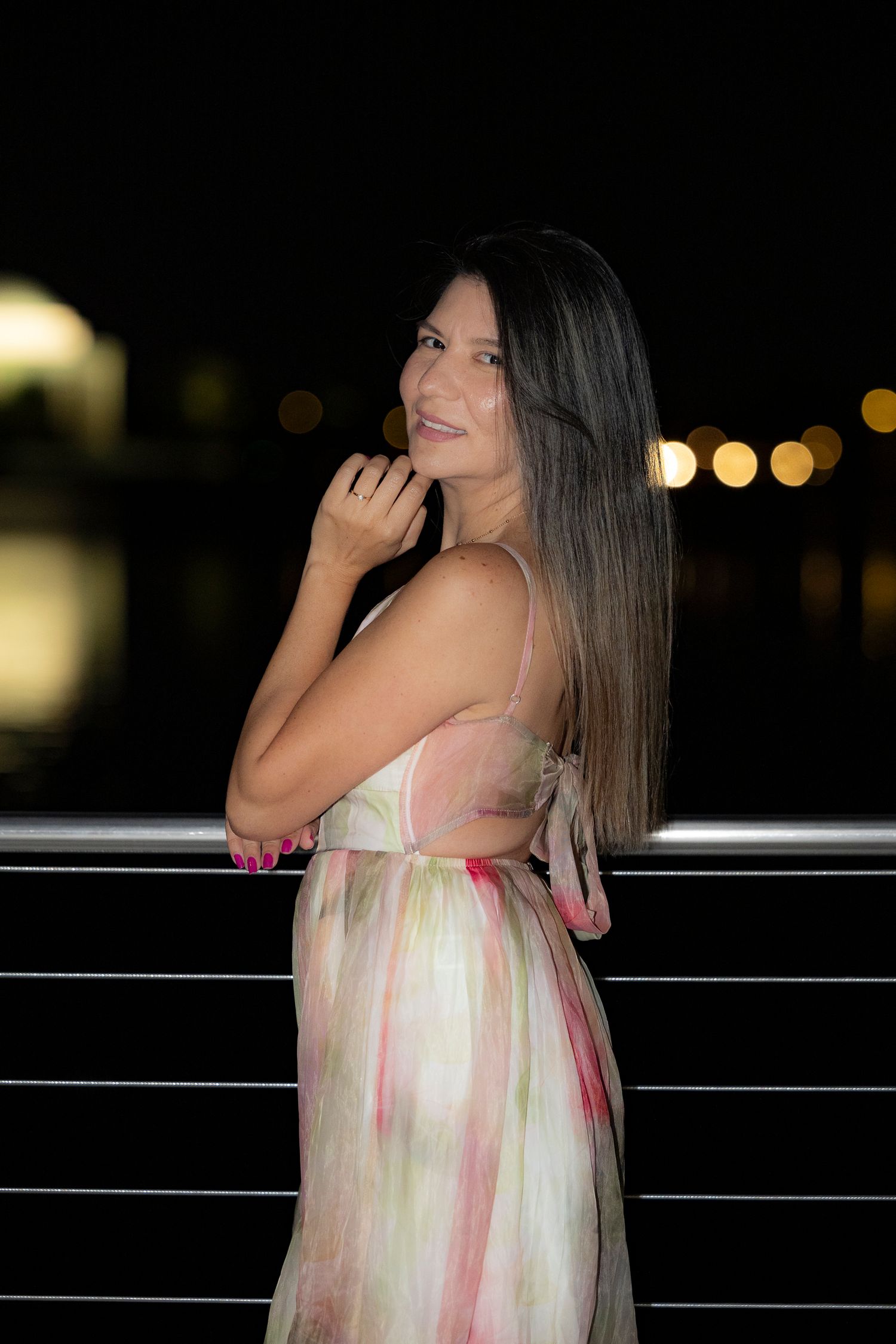 Ethereal cream and pink dress photographed at night with bokeh lights in background.