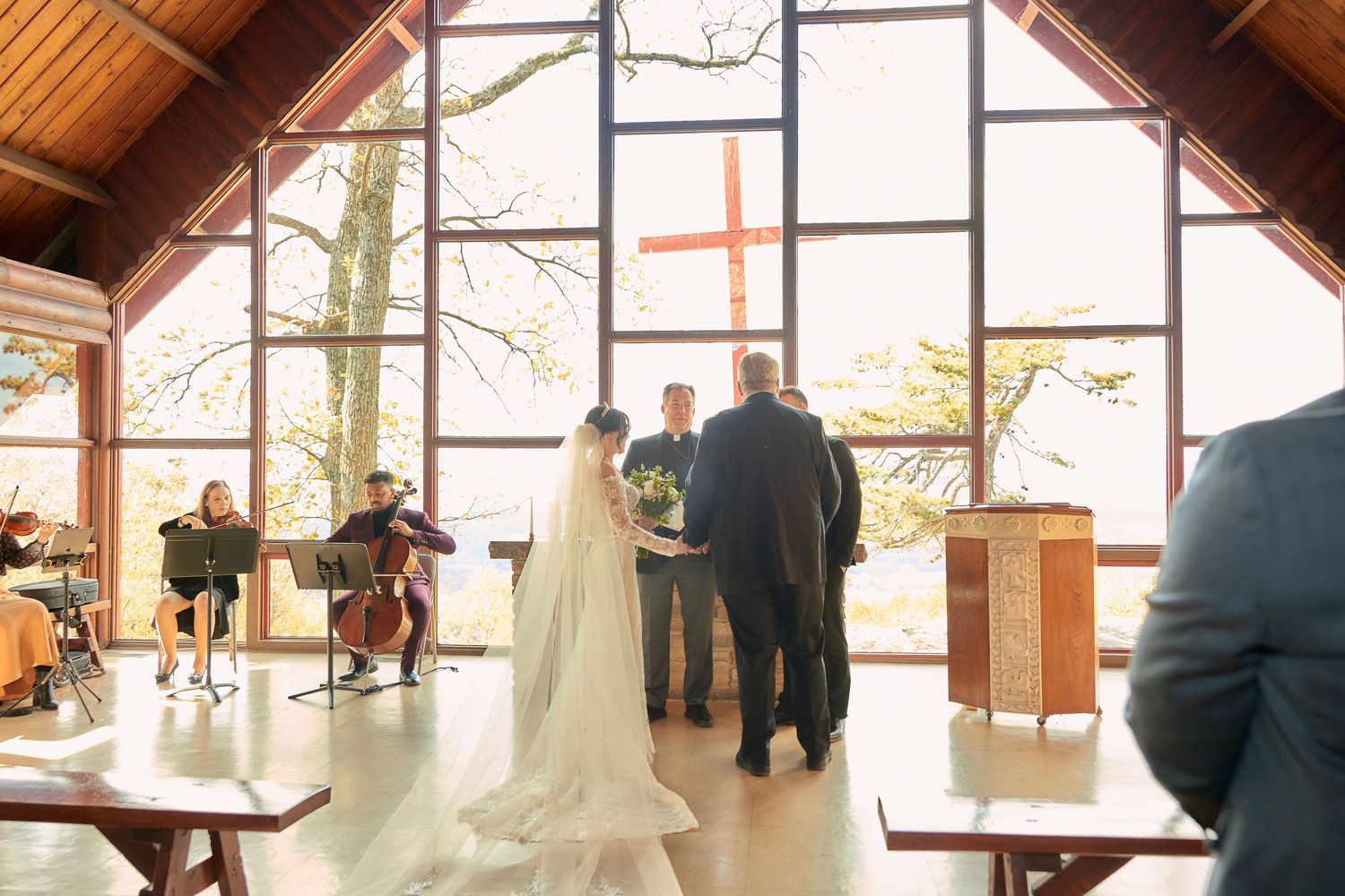 Interior of a rustic wooden chapel with large windows and natural light streaming in.