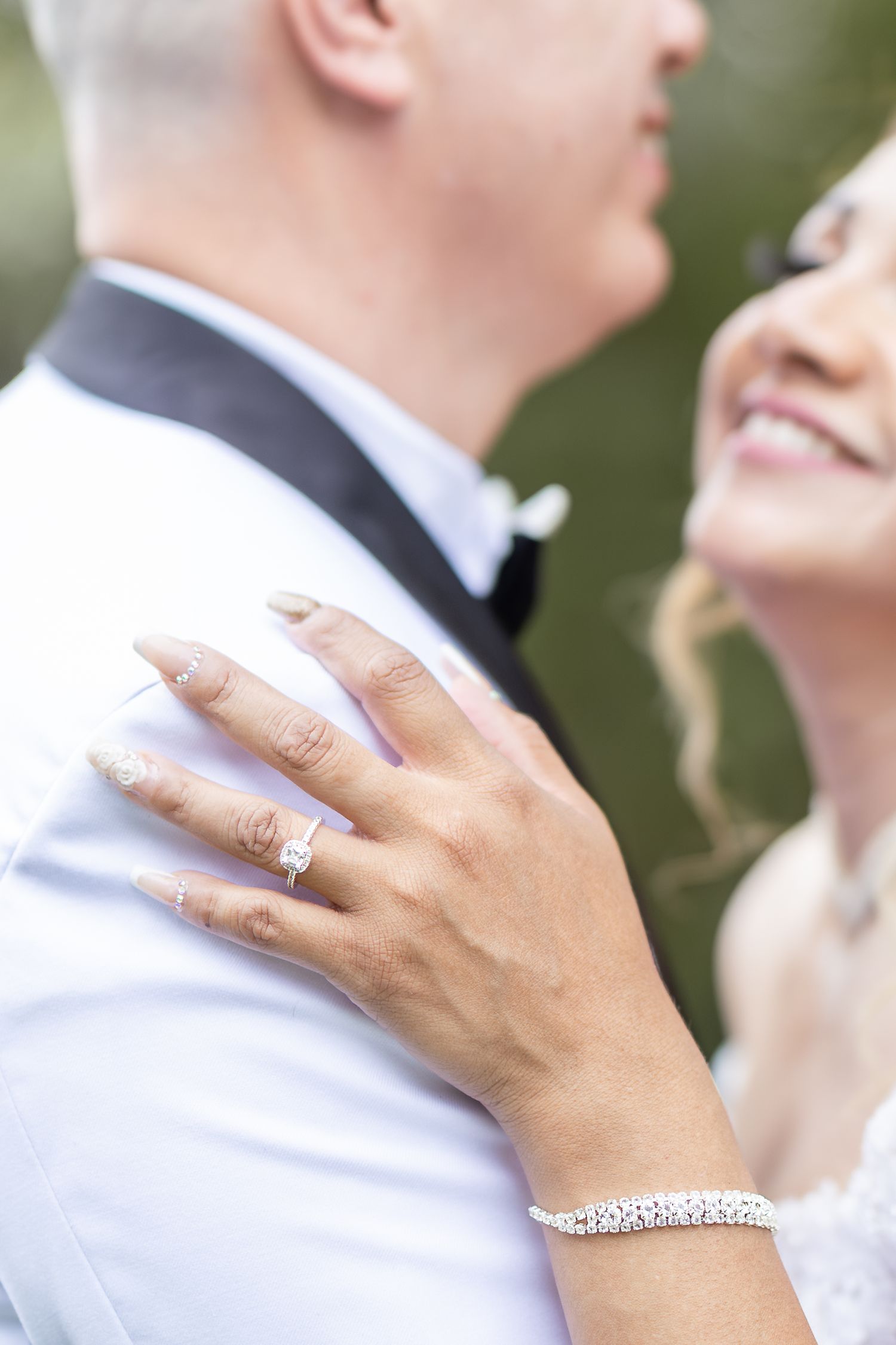 Close-up shot of hands wearing elegant wedding rings and bracelet against a formal white dress shirt.