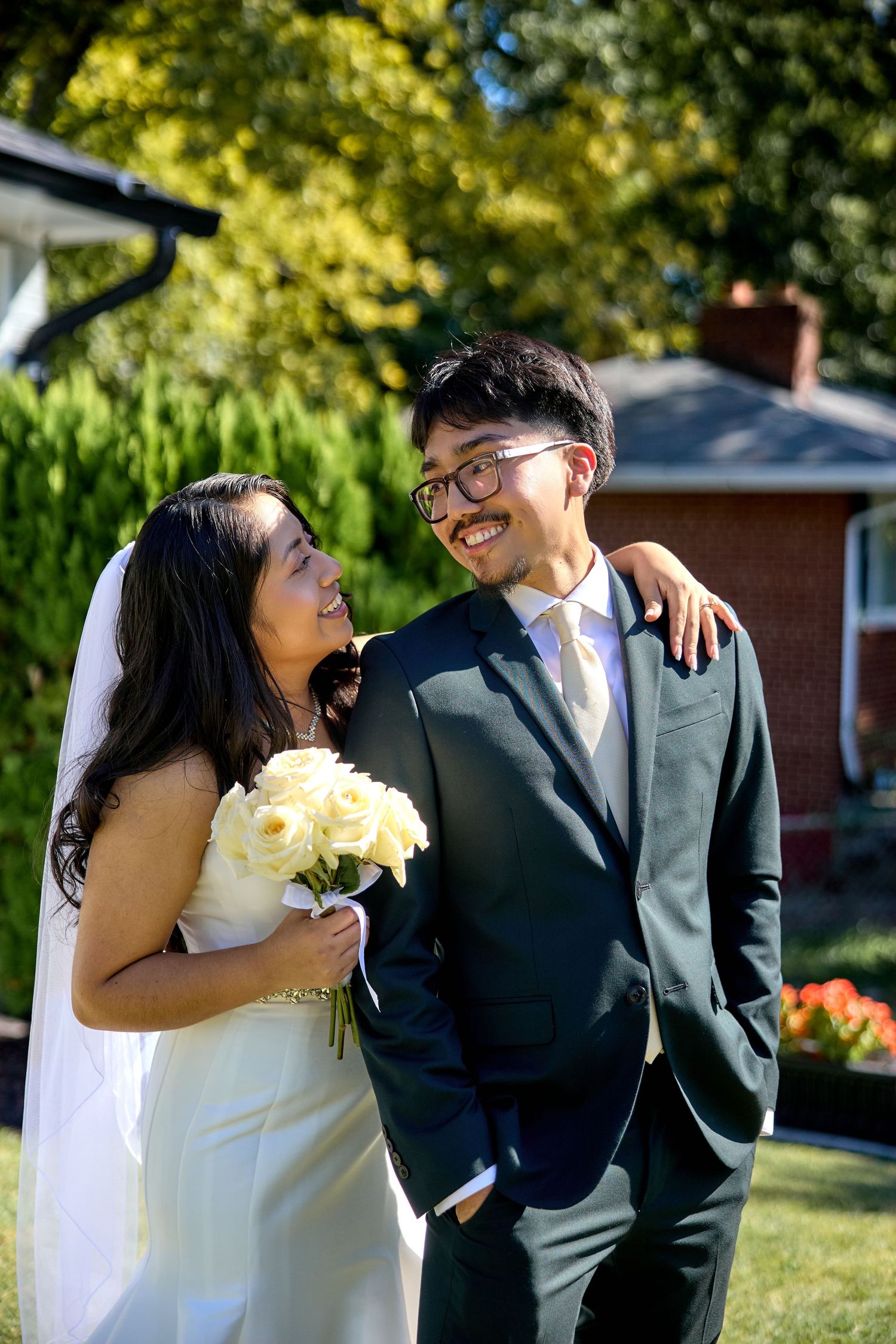 A couple sharing joyful moments outdoors on a sunny day with yellow flowers.