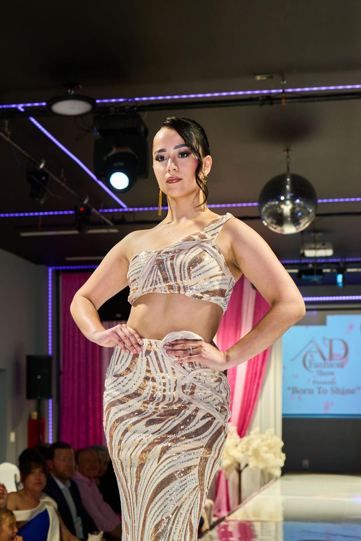 Model walks runway in beaded two-piece crop top and skirt at ND fashion show Born To Shine event.