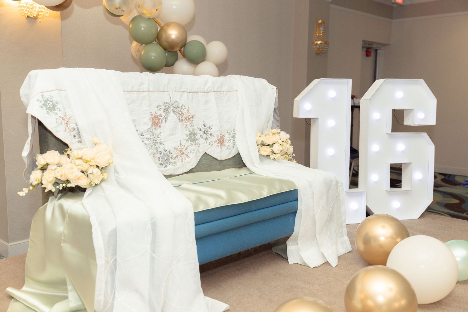 Quinceanera decoration setup with white draping, large numbers, and balloon arch.