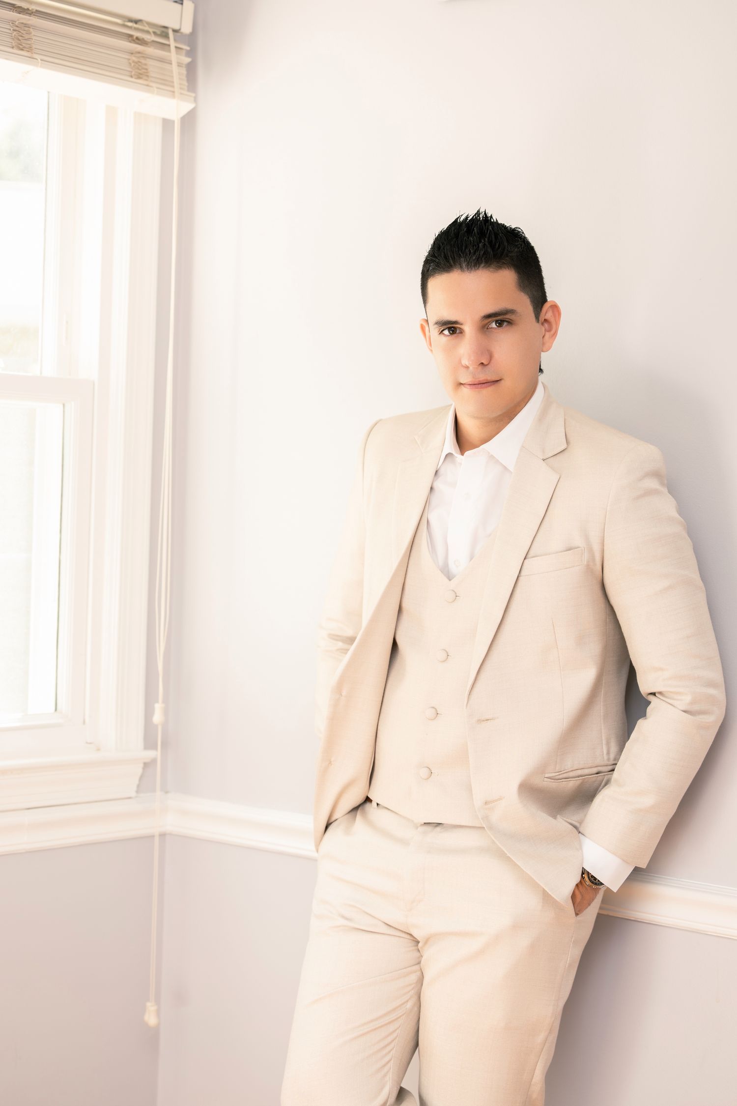 Professional fashion photo series showing a light beige suit against a bright white interior setting.