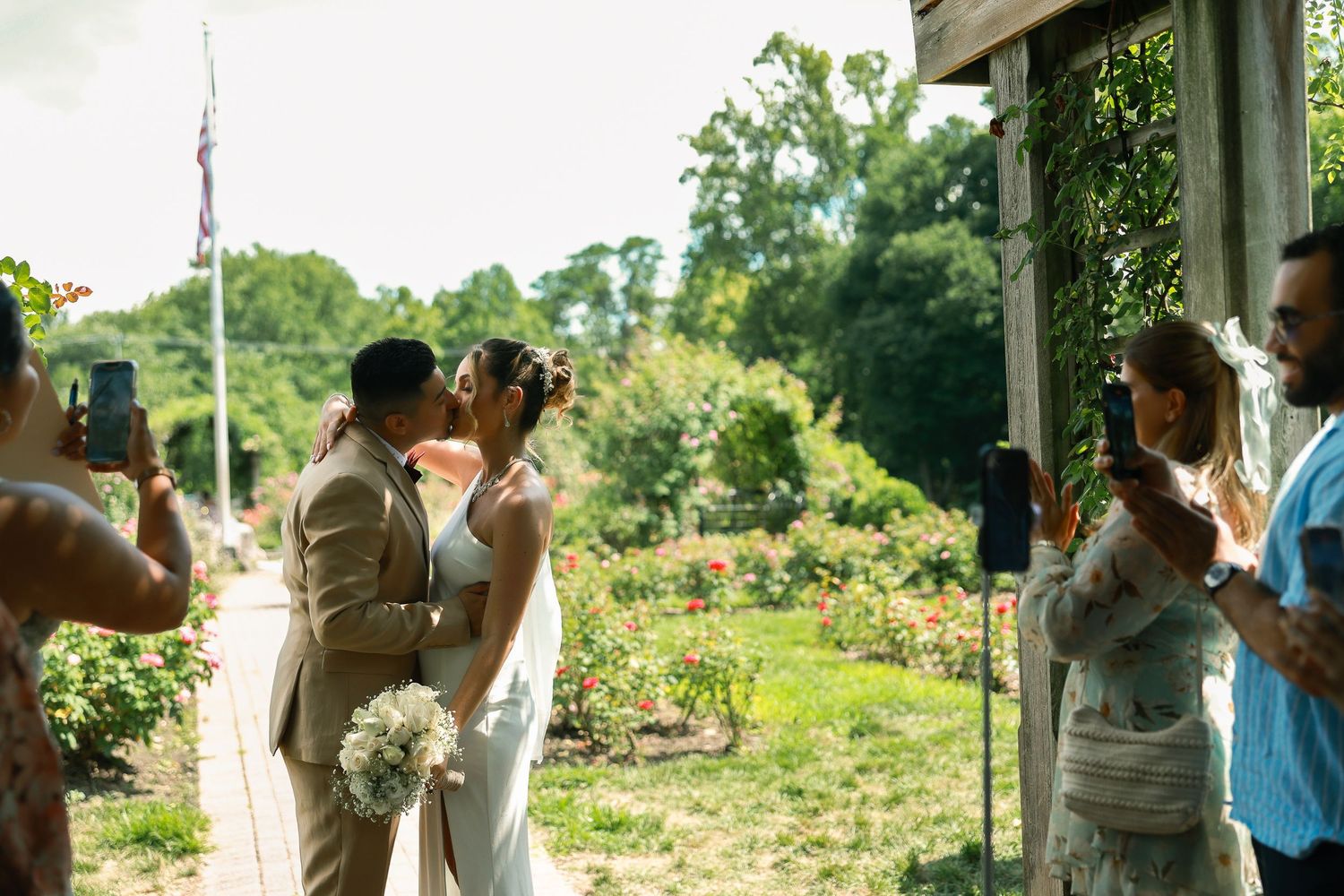 Wedding ceremony taking place in an outdoor garden setting with guests watching.