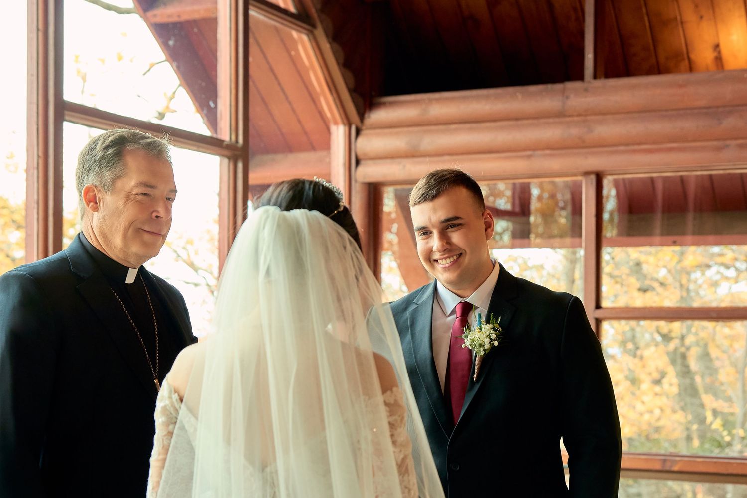 A traditional wedding ceremony unfolds in a rustic wooden chapel with warm natural lighting streaming through windows.