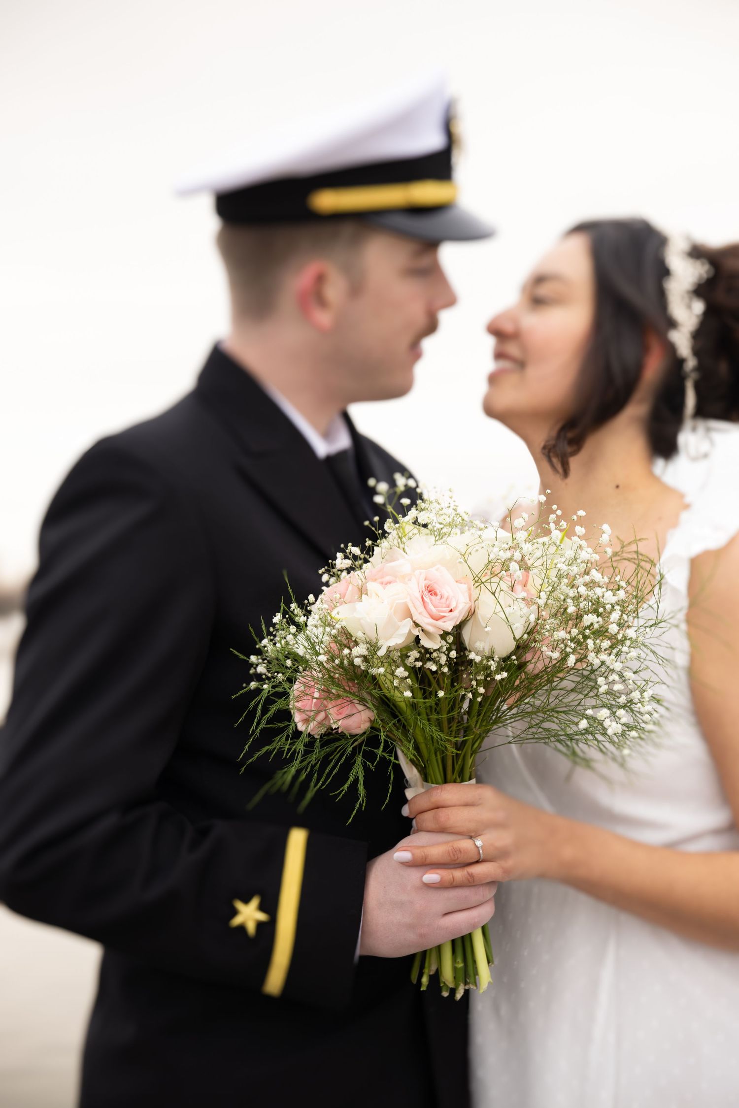 A couple shares a romantic moment with pink roses and baby's breath bouquet.