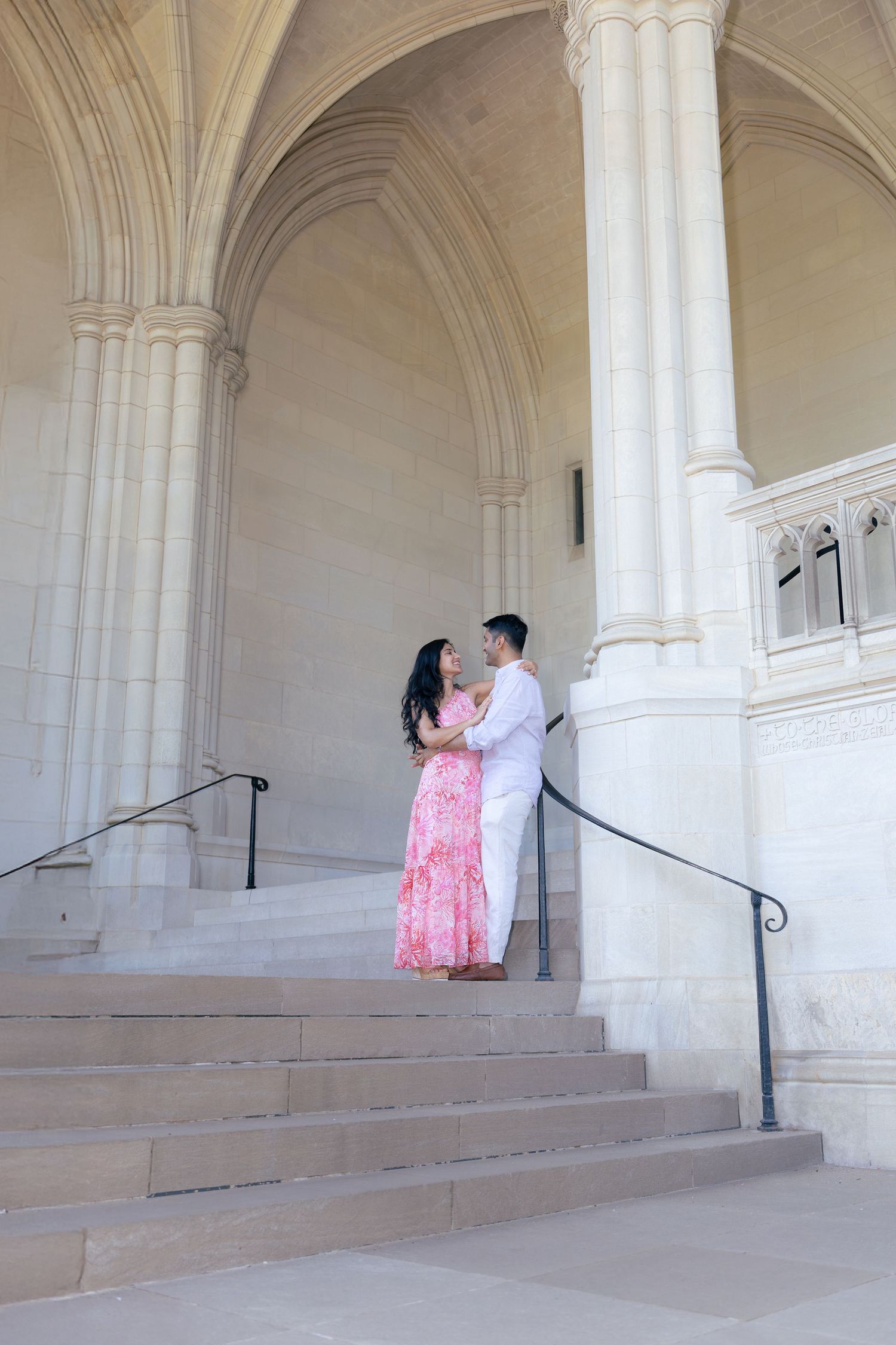 A romantic moment unfolds under white stone archways and columns on cathedral steps.