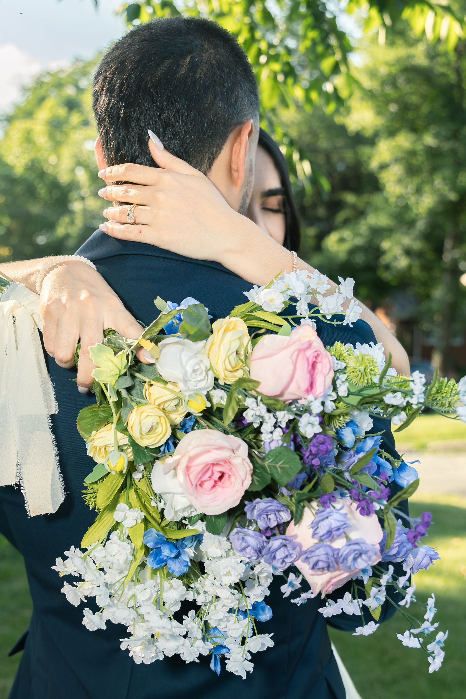Decorative floral arrangements in pink, blue, and white colors adorn an outdoor wedding setting.