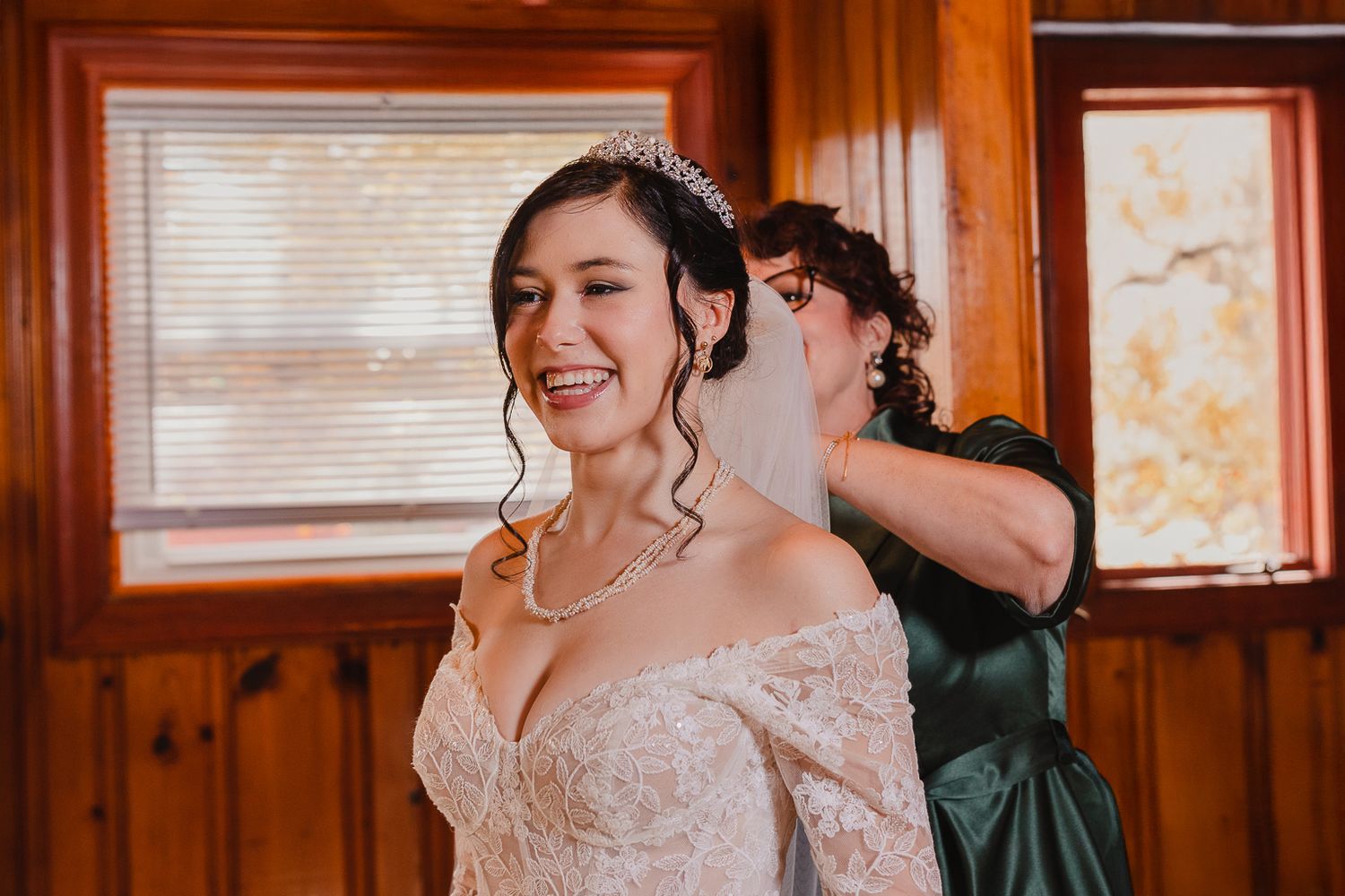 Wedding party poses in a warm-lit rustic wooden room with autumn sunlight streaming through windows.