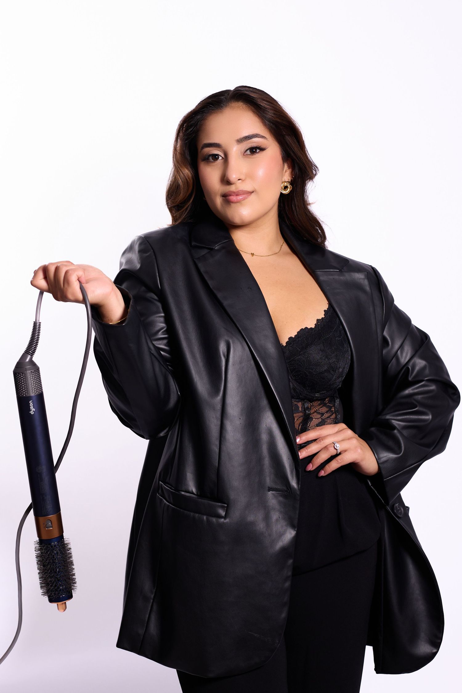 Model wearing black leather jacket and lace top poses confidently in studio photoshoot series.