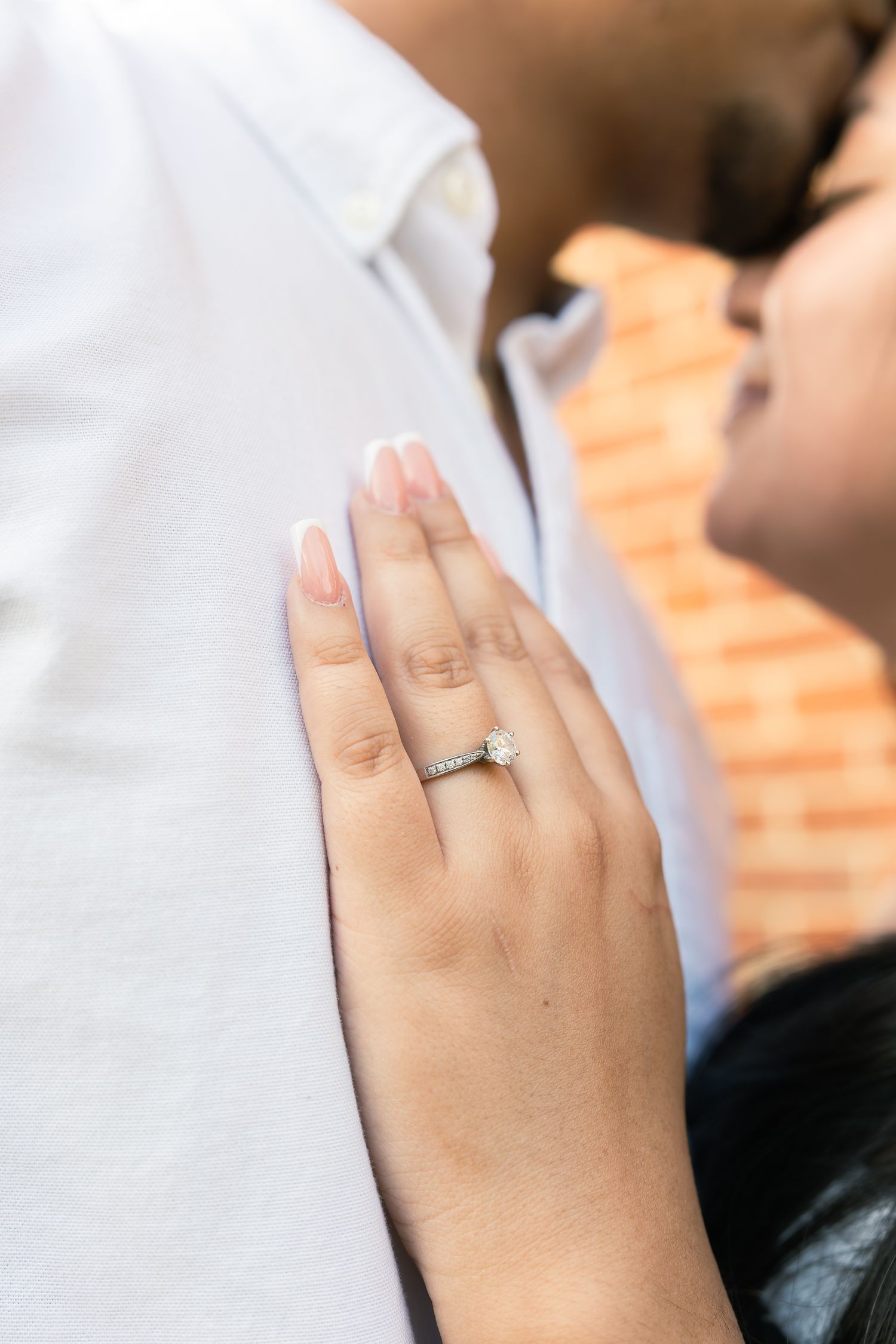 Close-up view of a hand wearing a silver wedding band on ring finger against a white background.