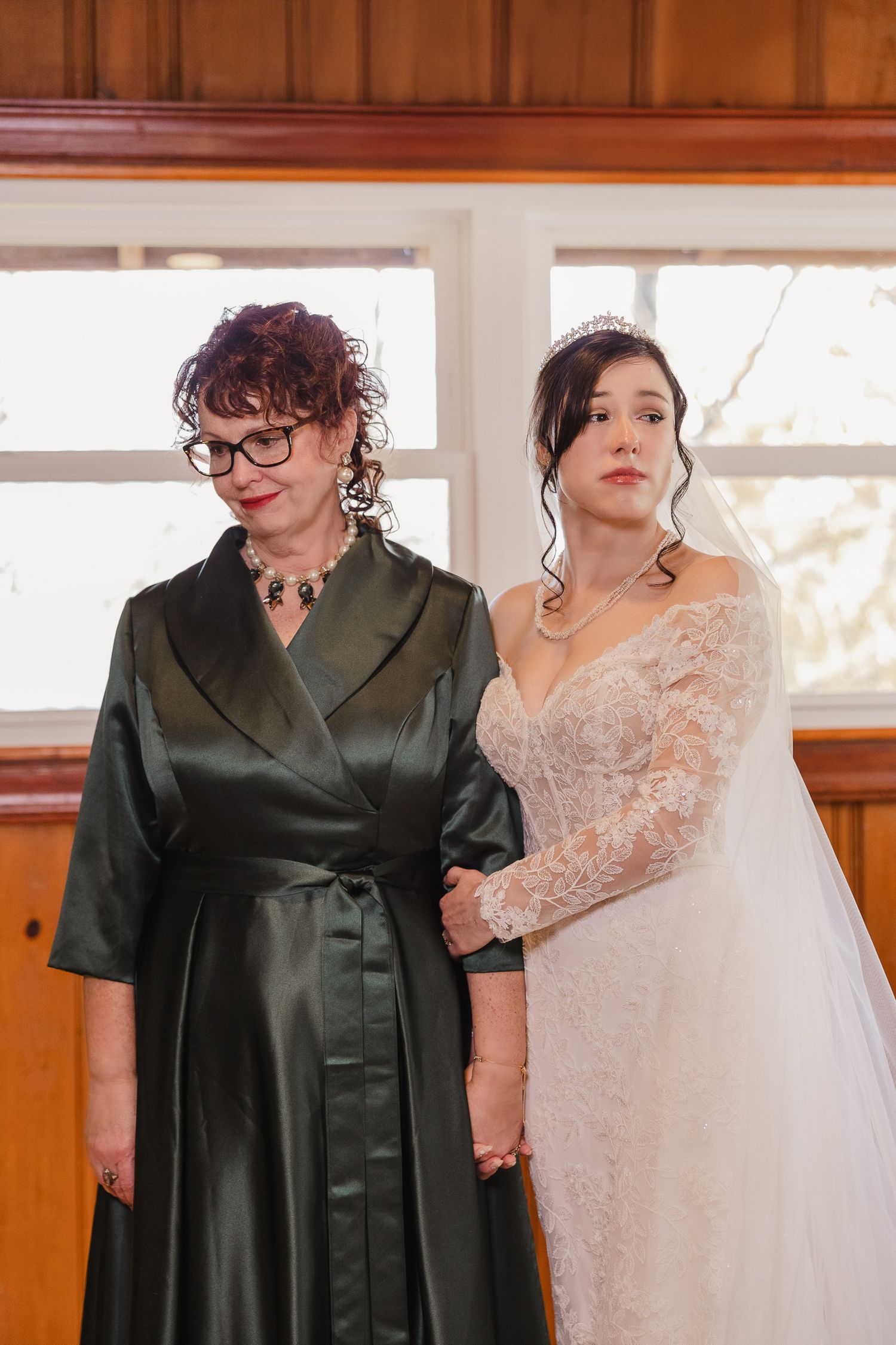 Two figures in contrasting black and white formal attire stand together in an elegant indoor setting.