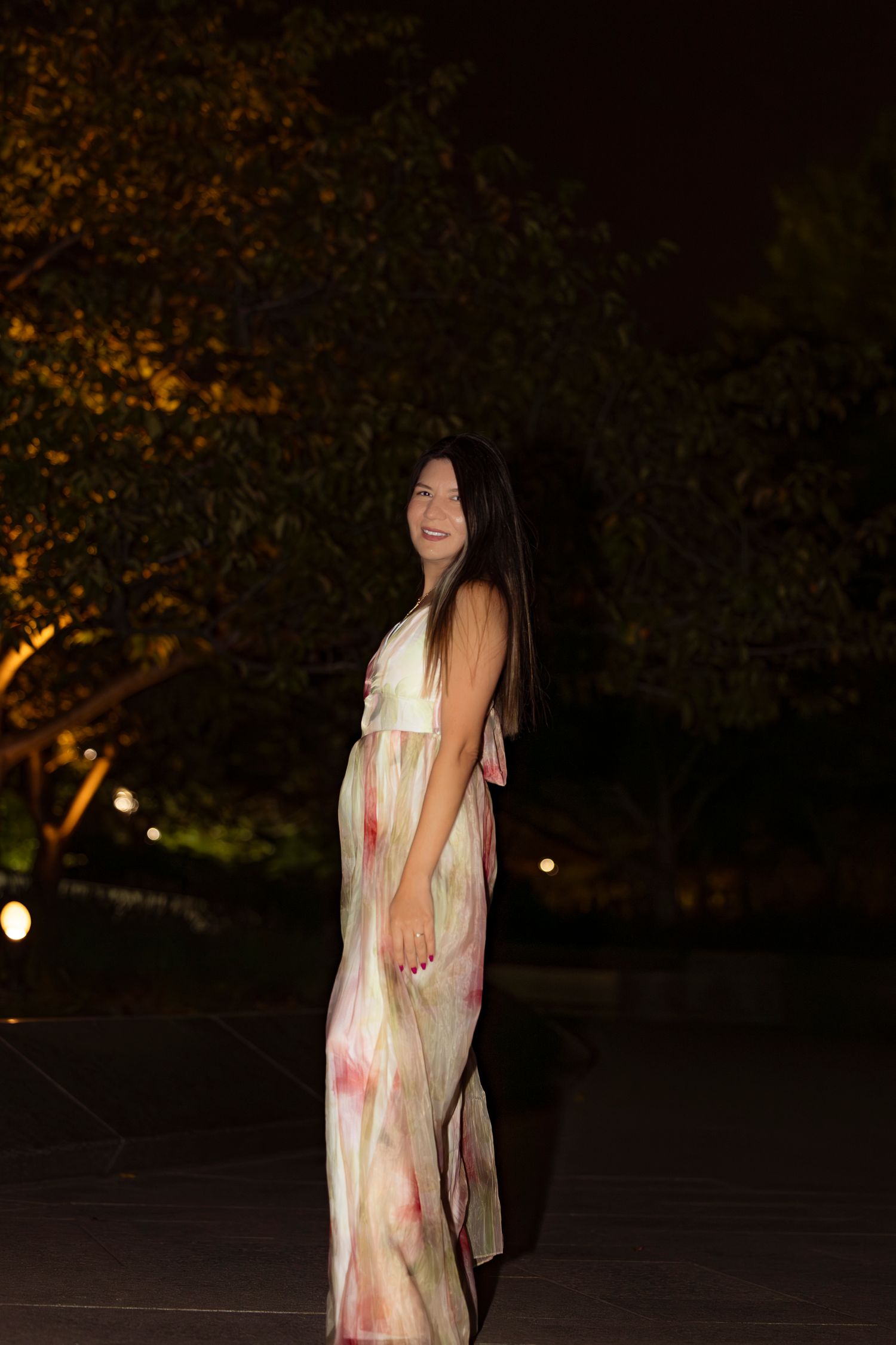 Long floral dress captured in nighttime garden setting with ambient lighting.