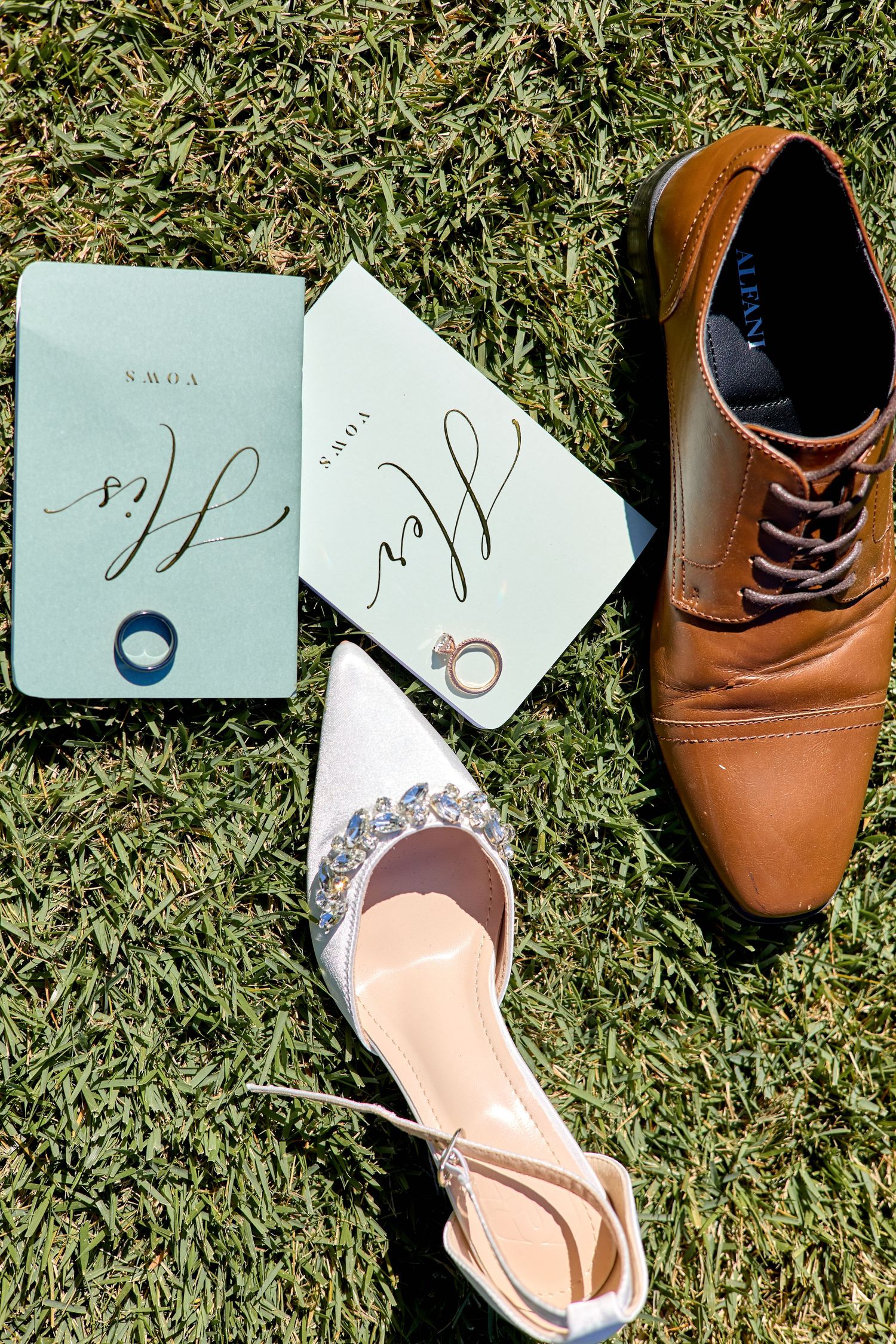 Brown leather dress shoes and handwritten notes arranged on green grass in sequence.