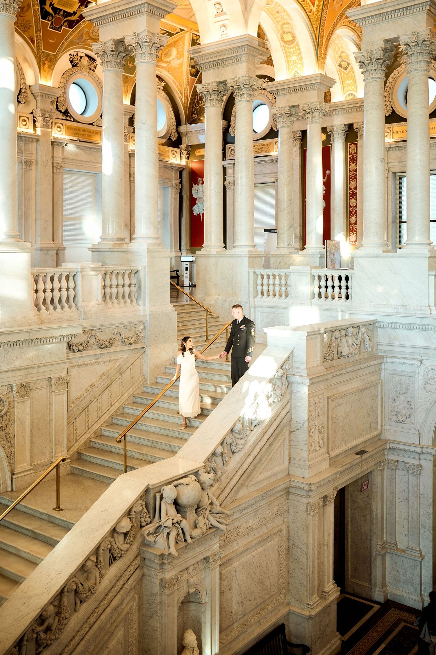 Bride and groom walk down grand marble staircase in the Library of Congress Thomas Jefferson Building.