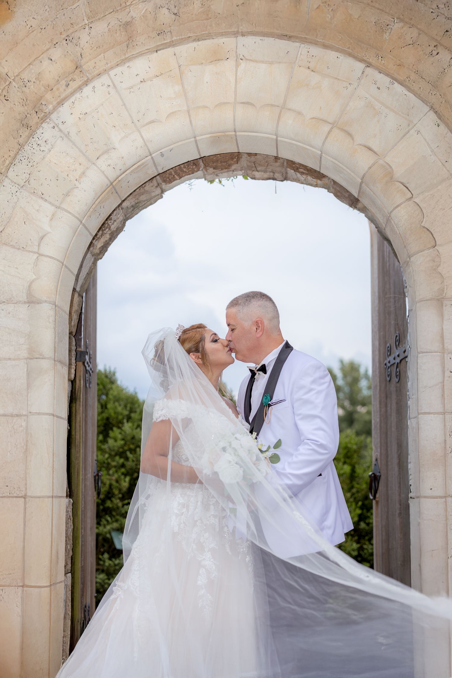 A romantic wedding couple shares tender moments under grand stone archways in a sequence of intimate poses.