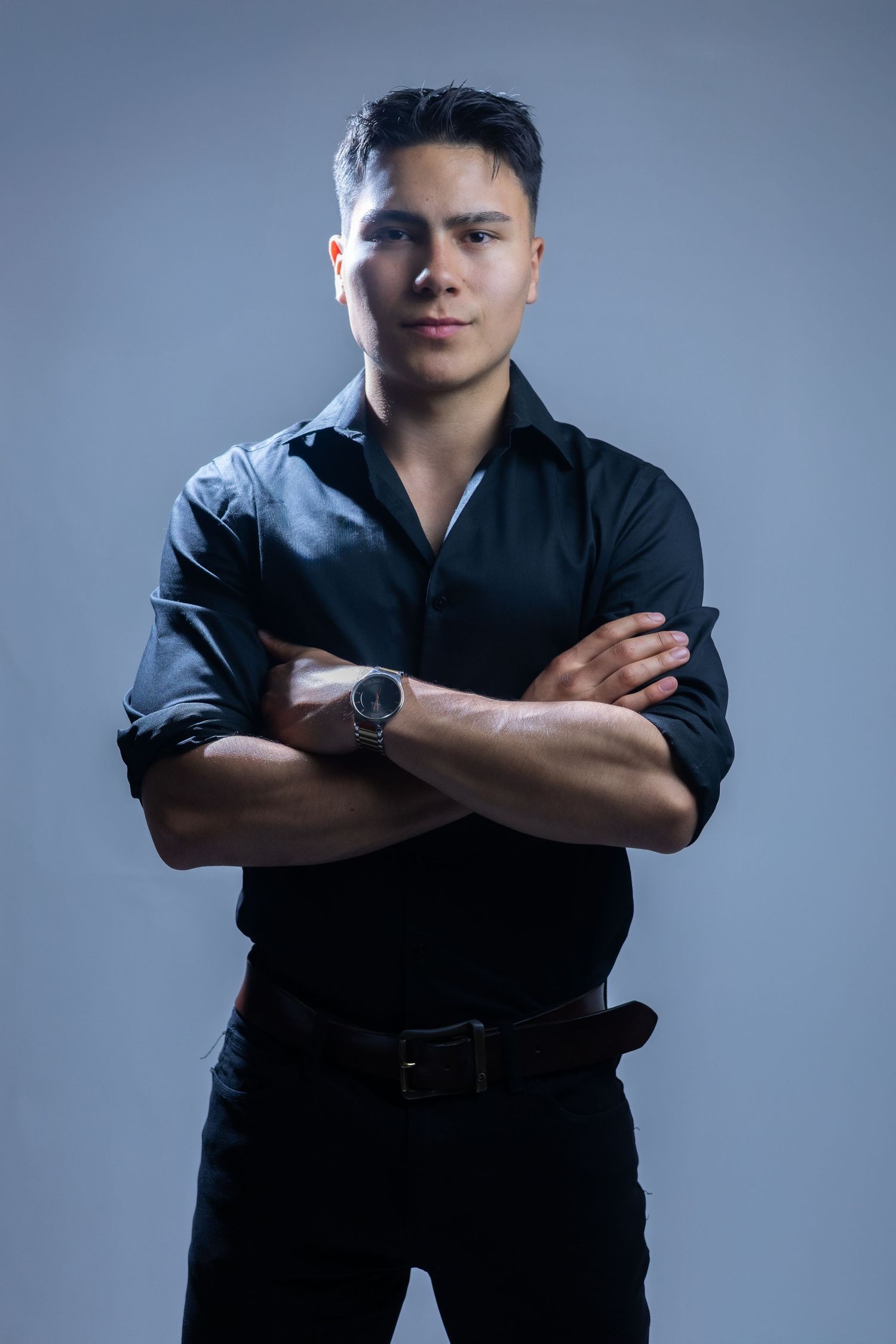 Professional portrait photo series showing figure in black against blue background with crossed arms and serious pose.