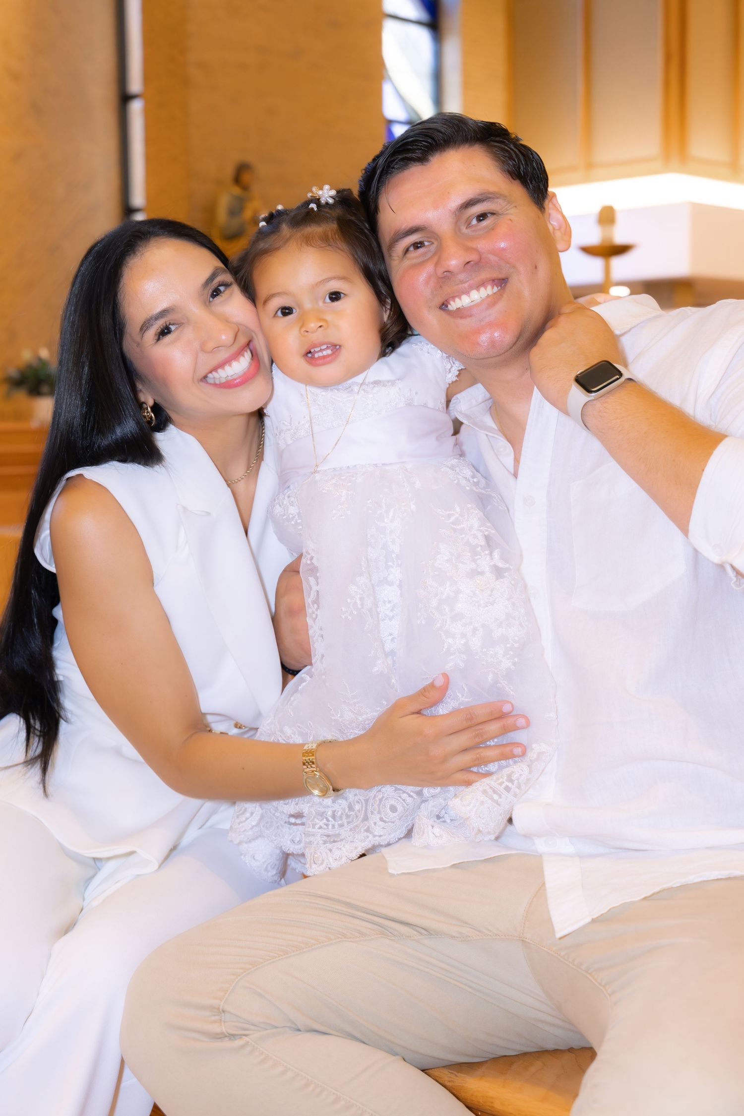 A happy family poses together indoors wearing coordinated white outfits.
