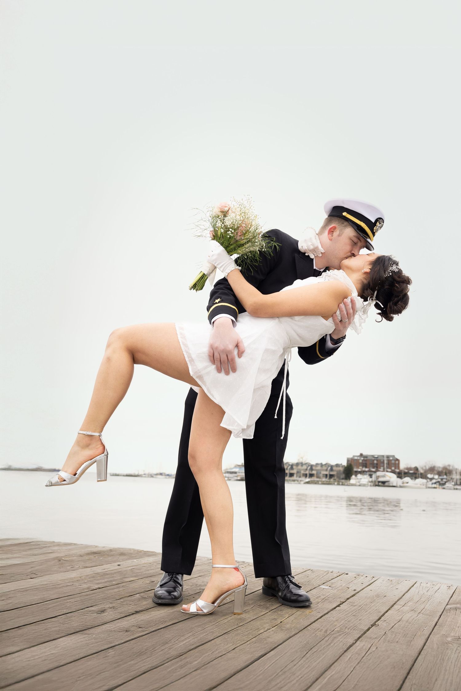 Romantic dip pose between couple on wooden dock by waterfront.