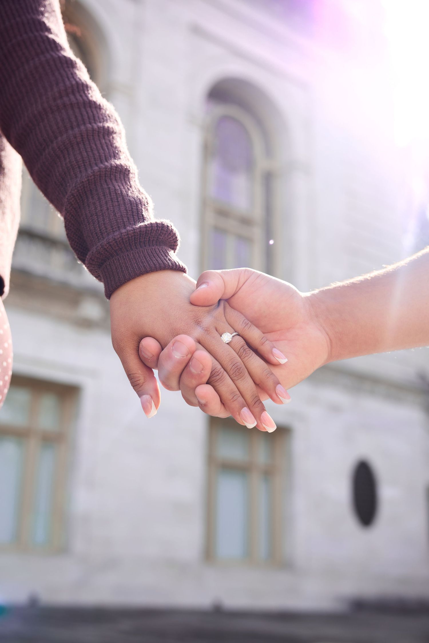 Two hands gently clasping together in a romantic gesture against a soft blurred background.