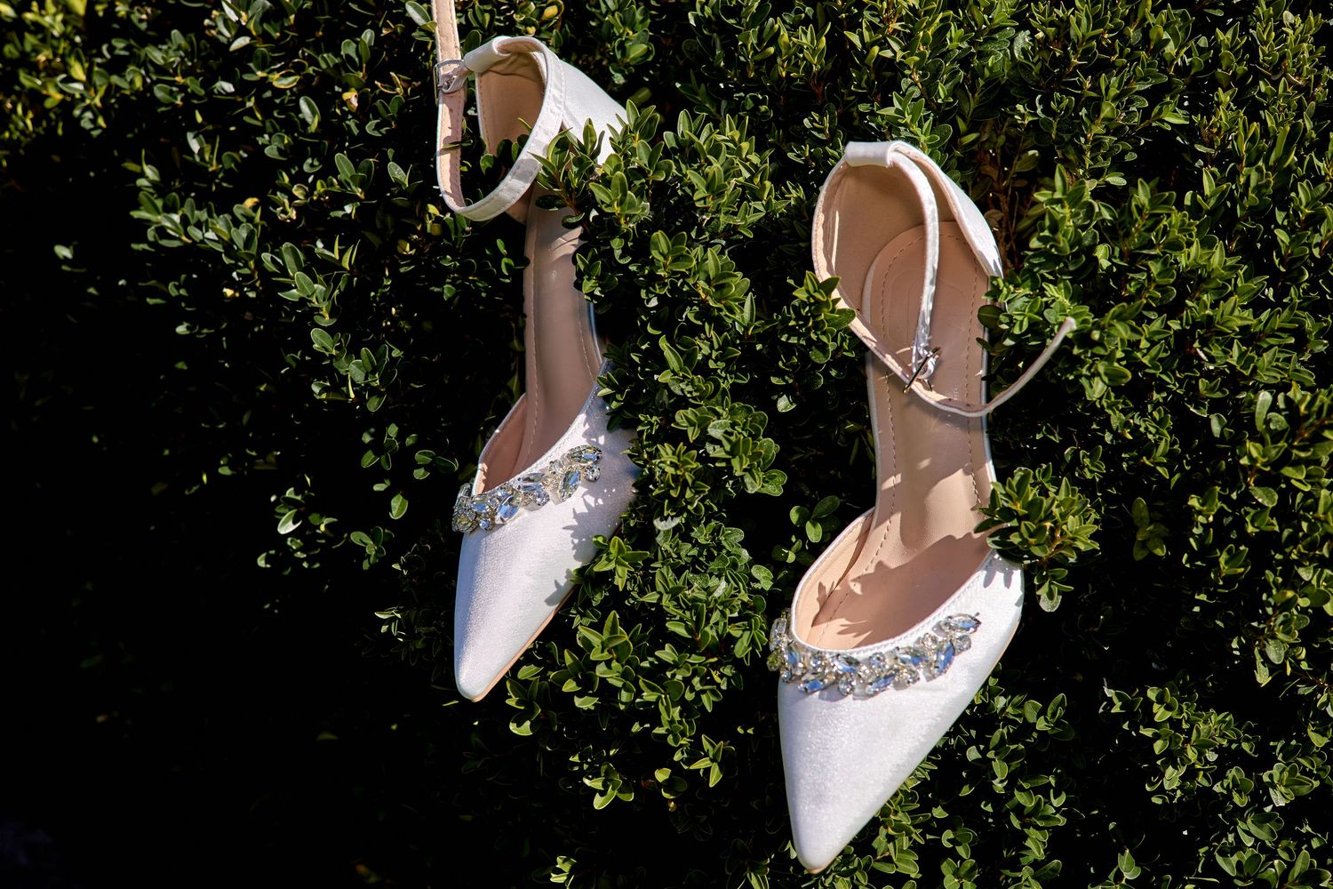 White and brown wedding shoes displayed with mint colored cards on grass.