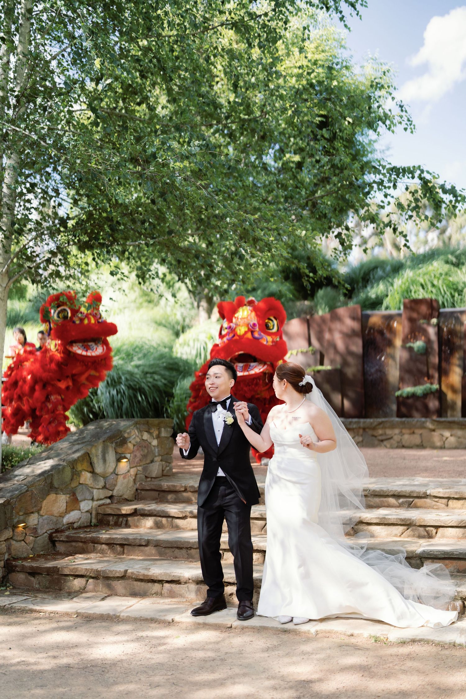 Wedding celebration featuring traditional Chinese lion dance performers in a garden setting.