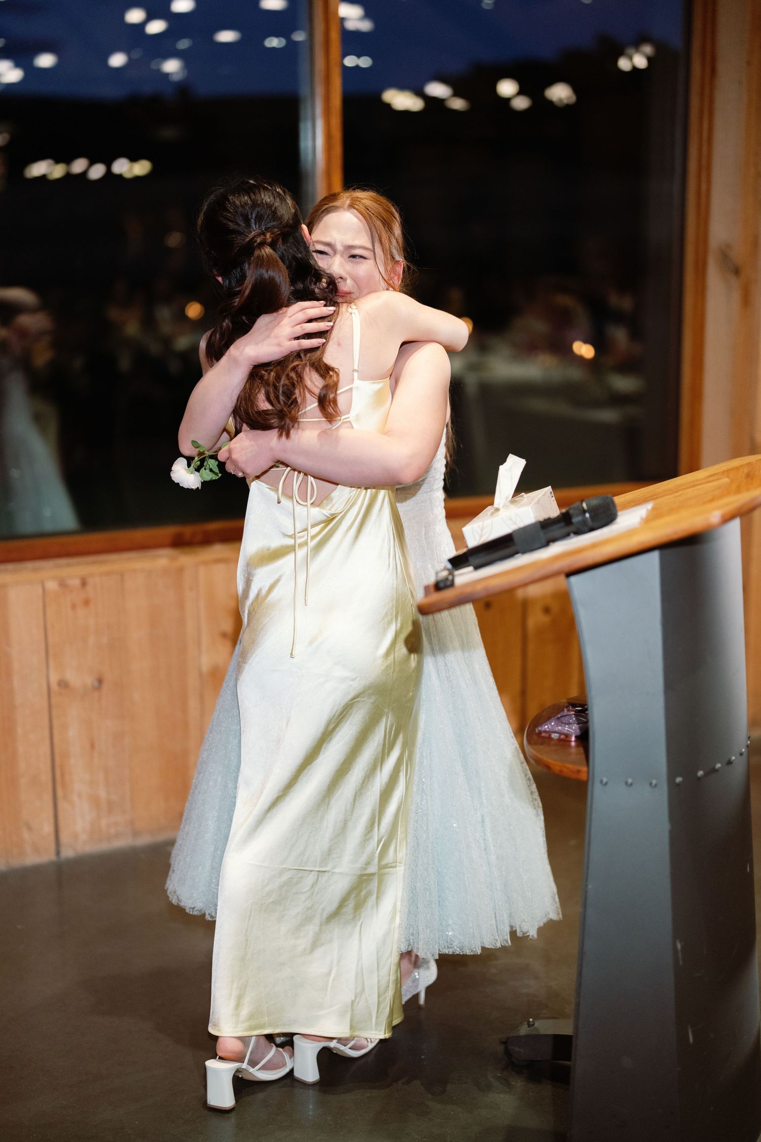 Wedding celebration candid moment of dancing and embracing in wooden venue at night.