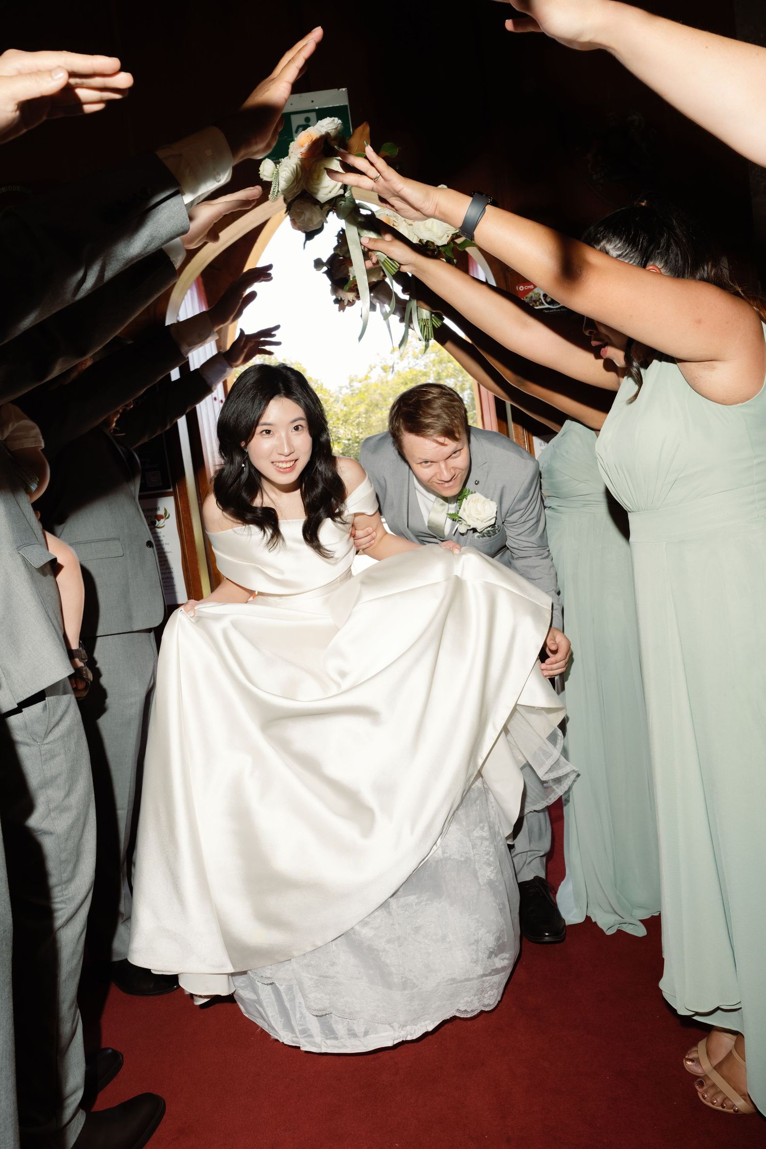 Wedding guests dance together at a reception, with people in white and gray attire moving energetically on the dance floor.