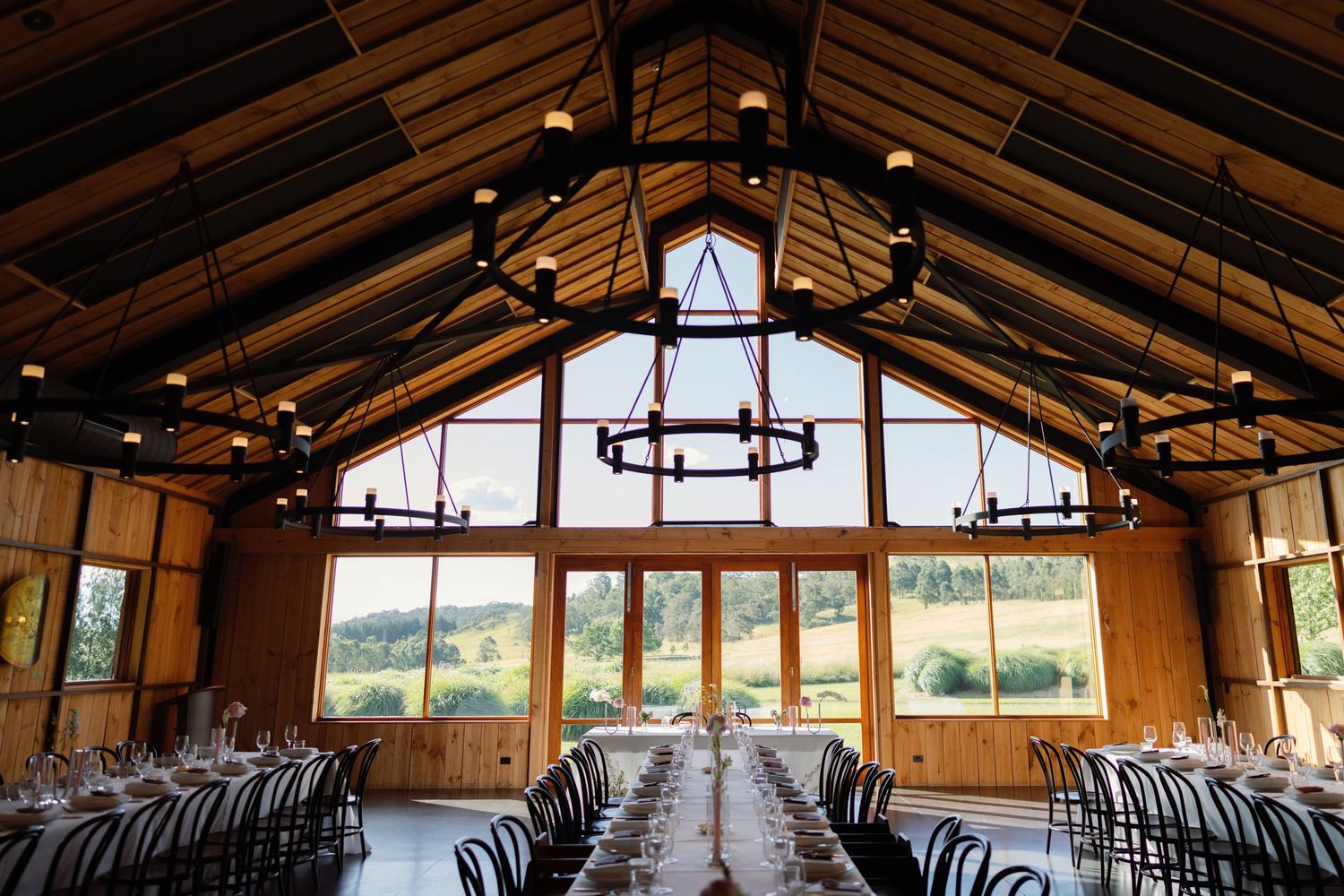 Interior panorama of a rustic barn wedding venue with wooden beams and large windows.
