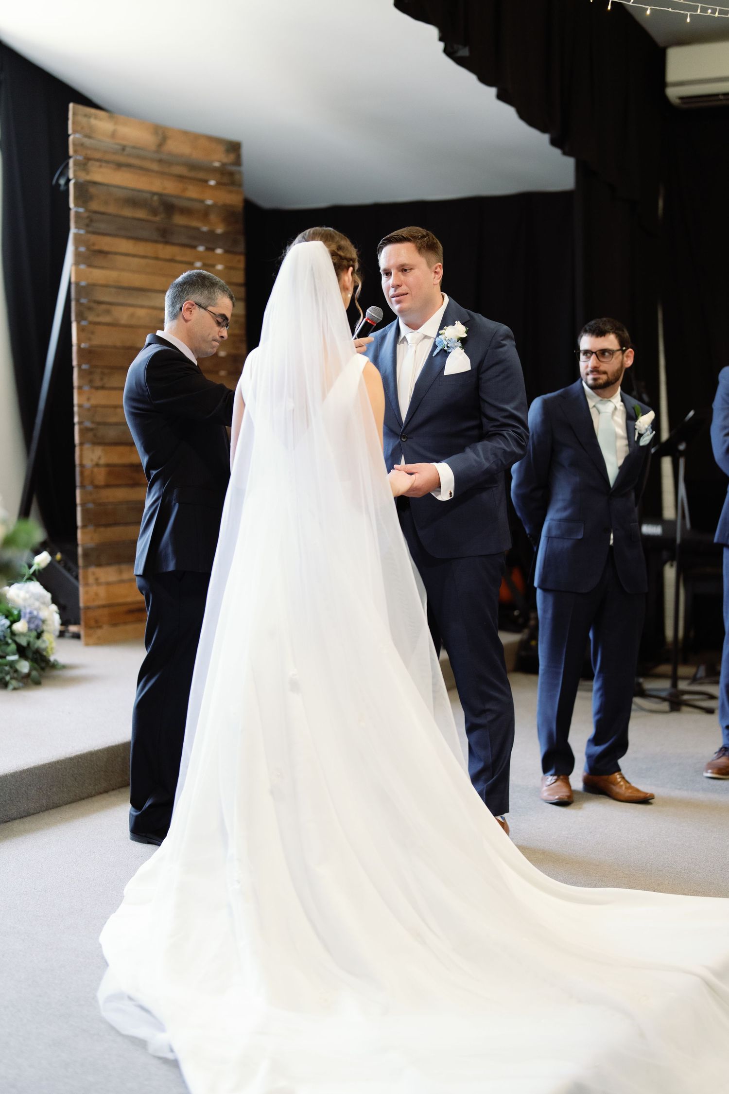 Wedding couple interacts playfully in an elegant venue with dark wood paneling and natural light.