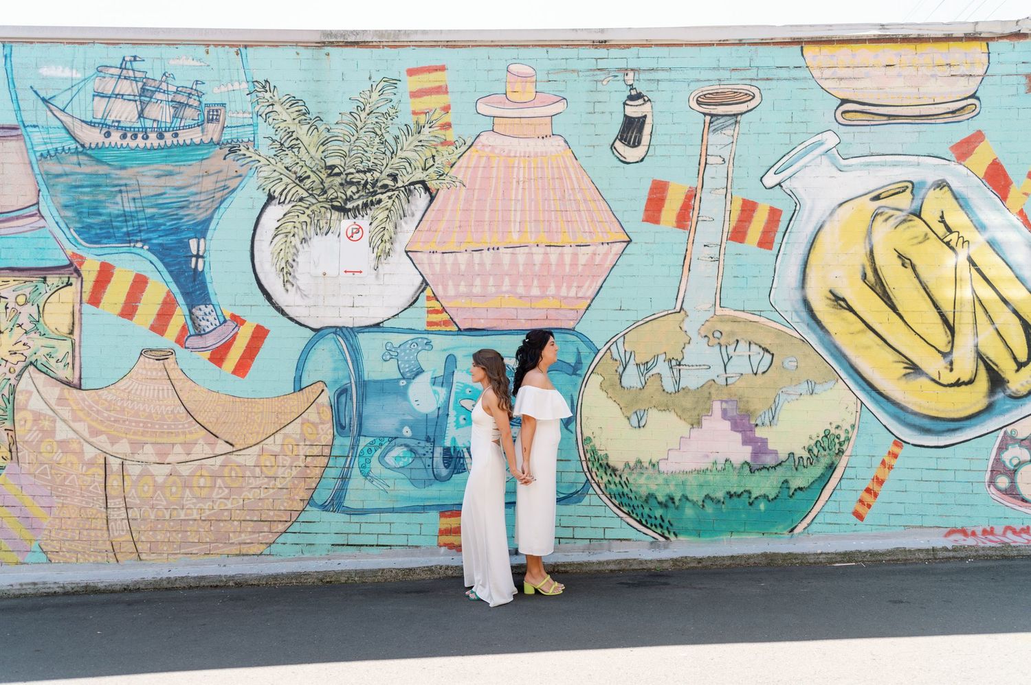 Colorful graffiti mural featuring playful cartoon characters and abstract designs painted on a long outdoor wall.