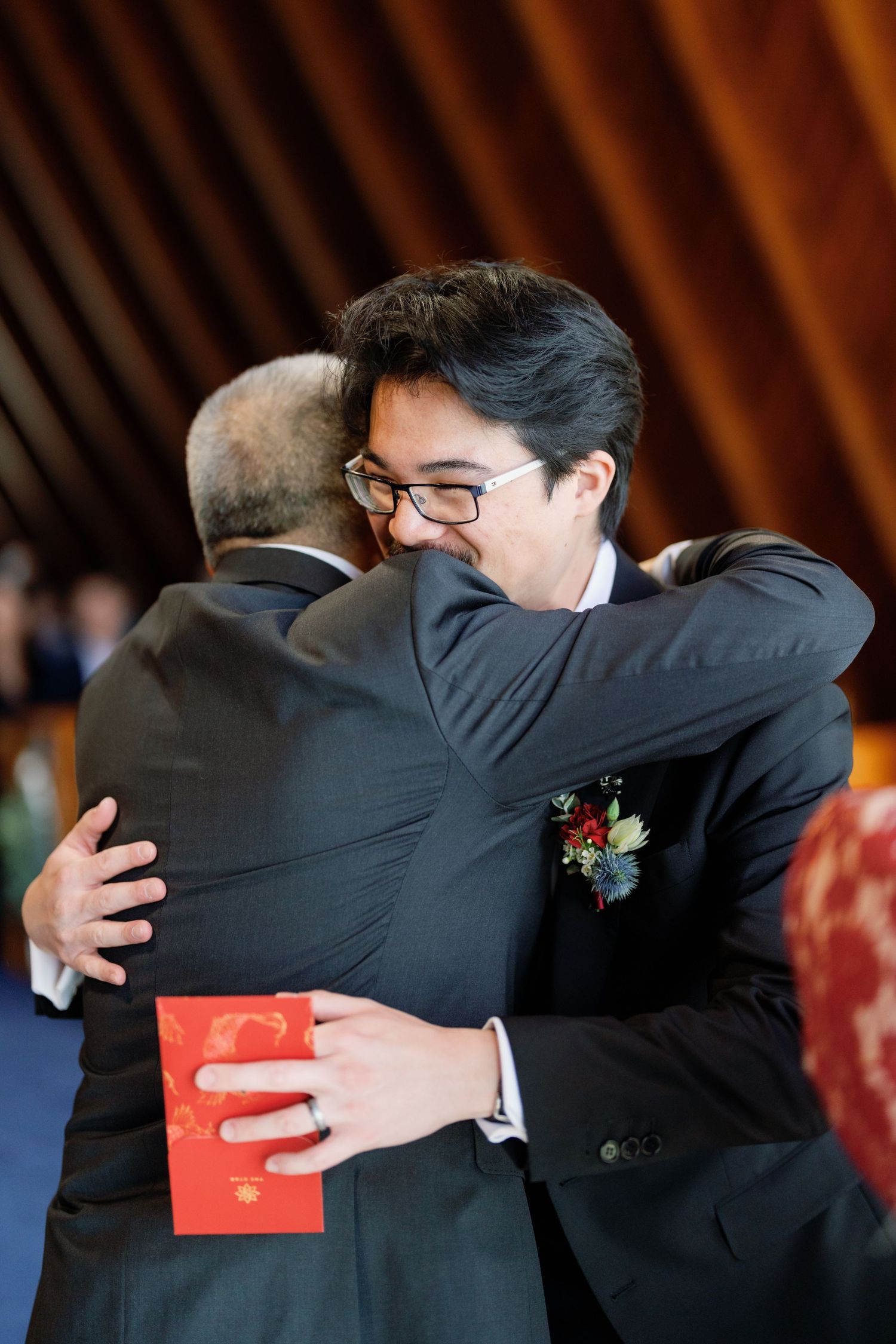 A series of emotional embraces between people in formal attire exchanging red envelopes at a celebration.