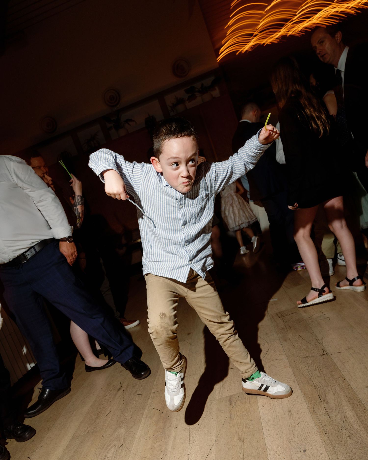 Energetic young boy dancing and jumping at a wedding reception party on the dance floor.