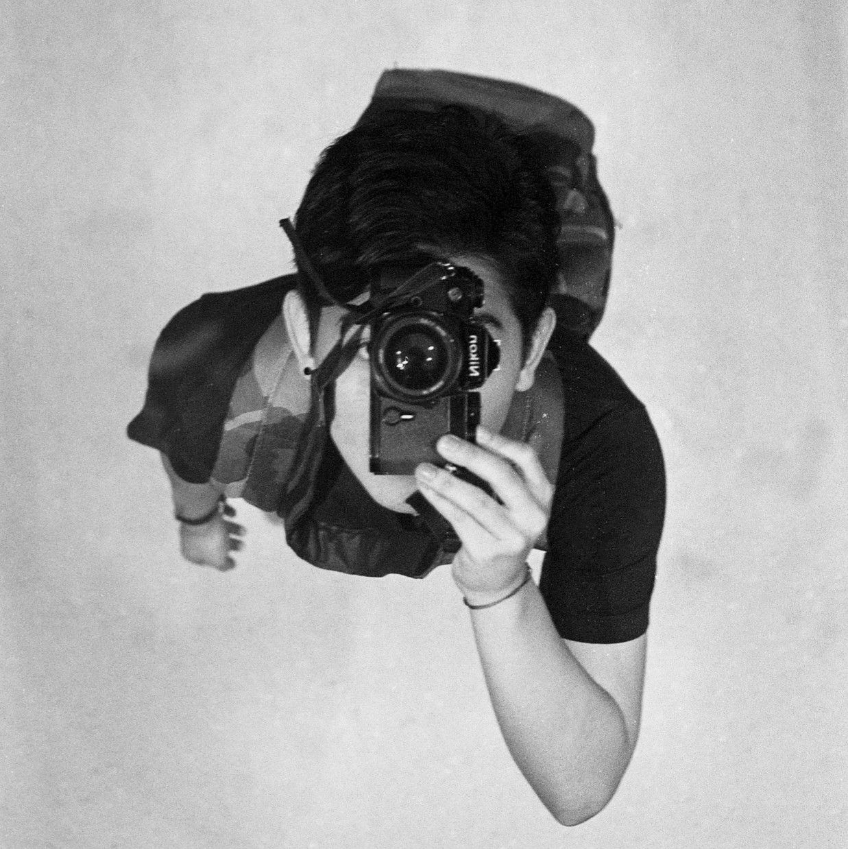 Black and white photo of someone taking a mirror selfie with a vintage camera.