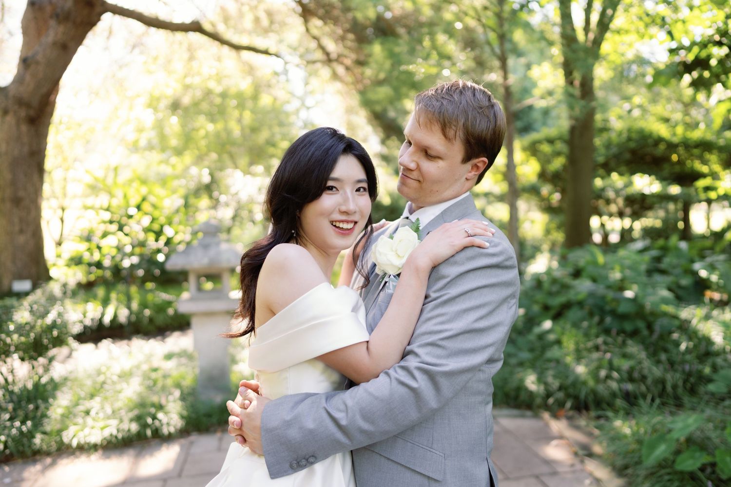 A couple shares joyful moments while dancing together in a sunlit garden setting.