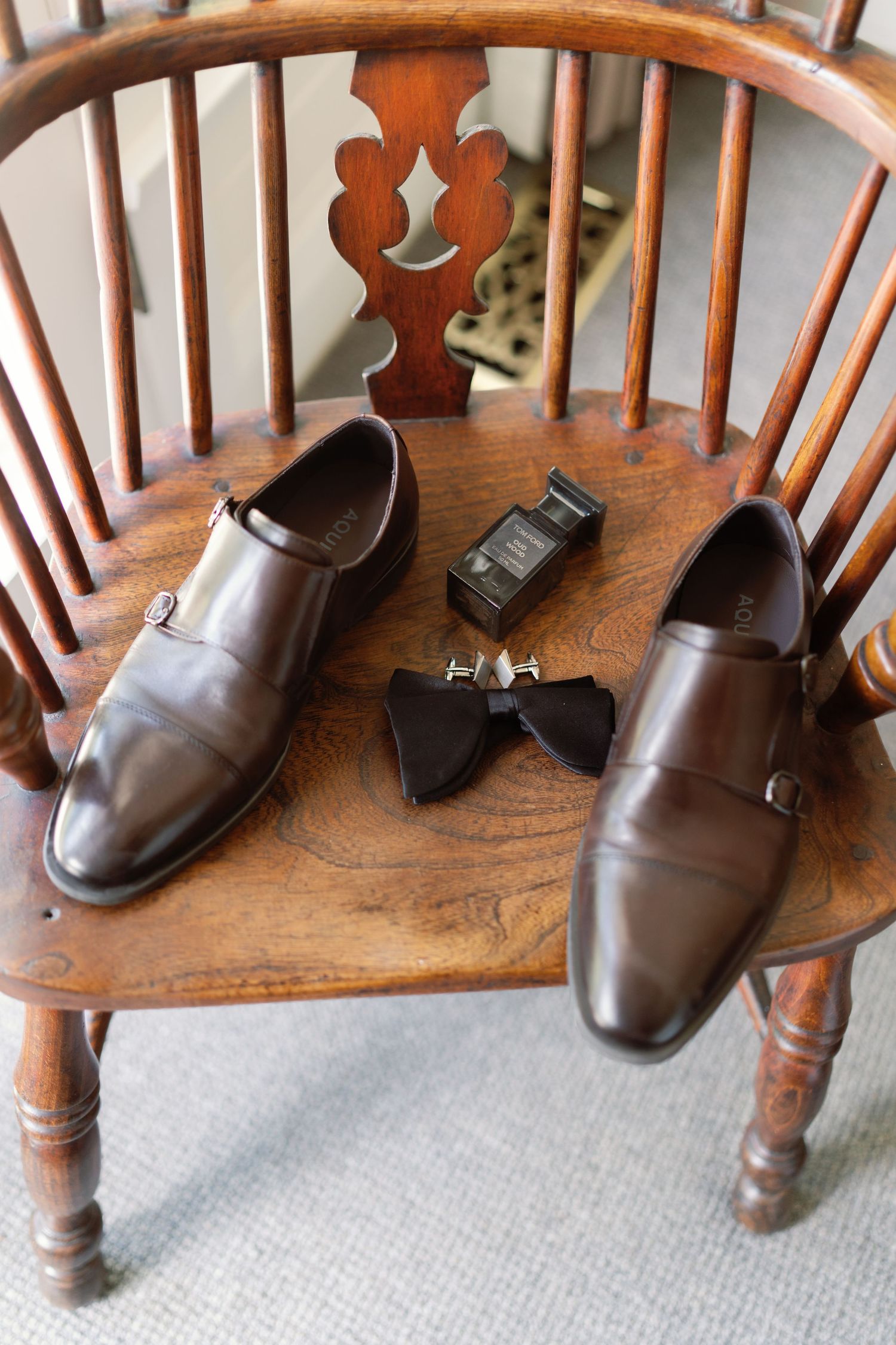 Brown leather dress shoes arranged on a wooden chair with spindles.