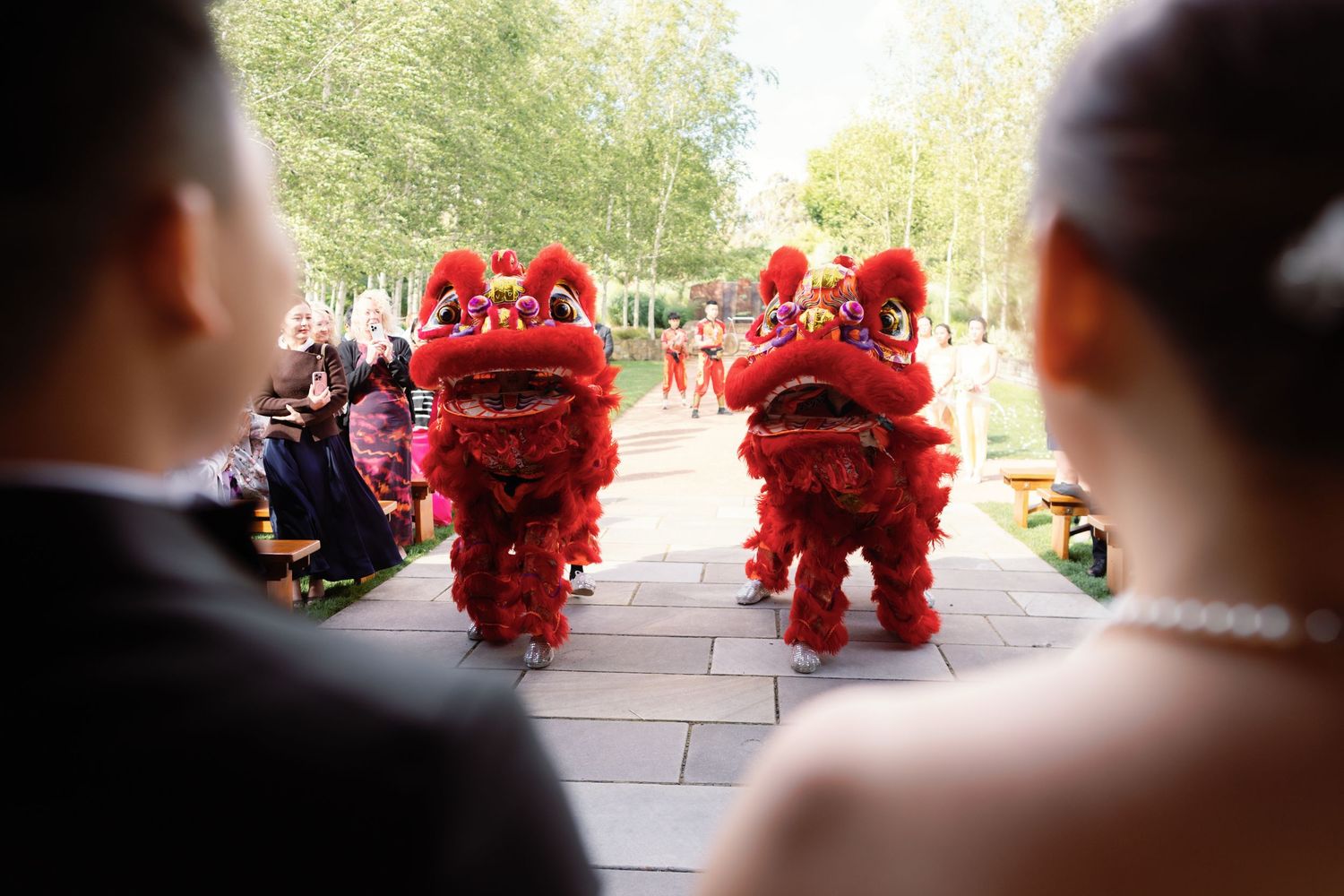 Traditional red lion dance performers entertain wedding guests during an outdoor celebration.