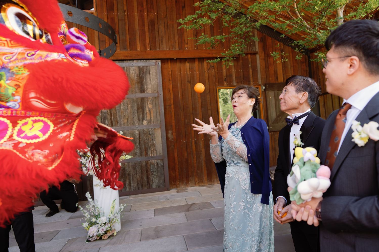 Red lion dance performers entertain wedding guests at outdoor celebration.
